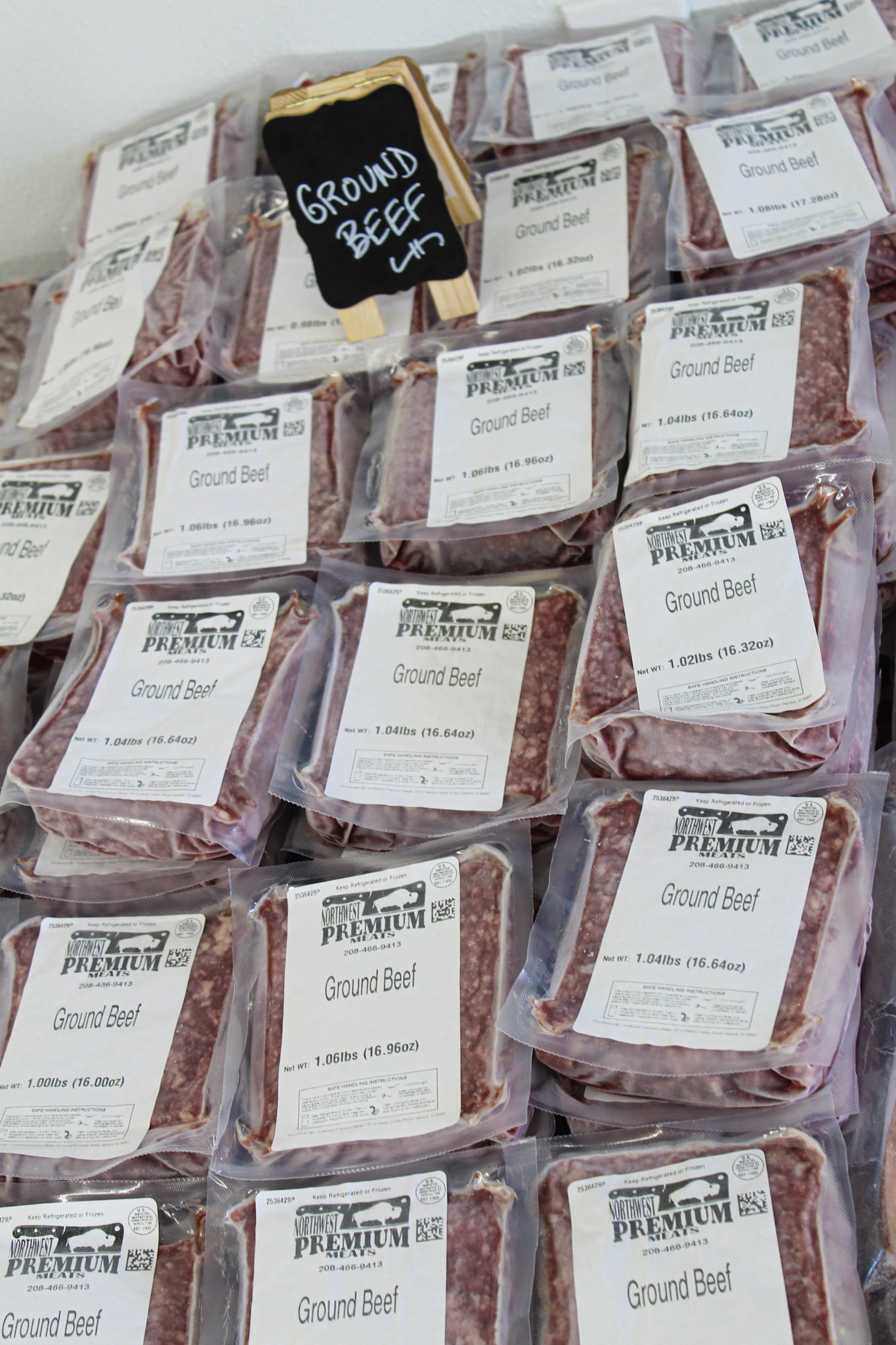 Multiple packages of grass fed corn finished ground beef with a small chalkboard sign that reads 'GROUND BEEF'.