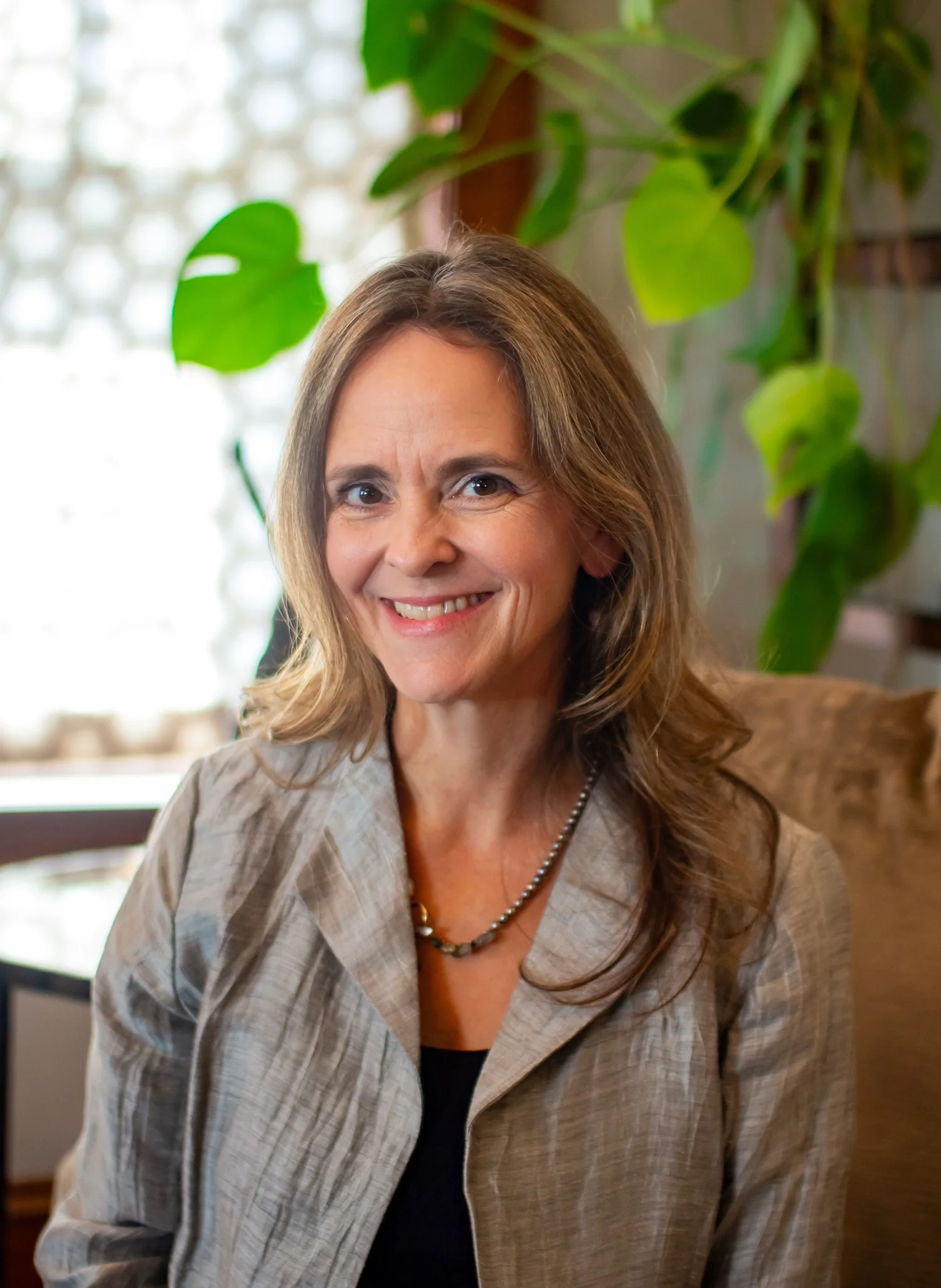 photo portrait of Siobhan O'Neill, MD, CGP sitting, smiling into the camera, with a green plant and a sunny window behind her.