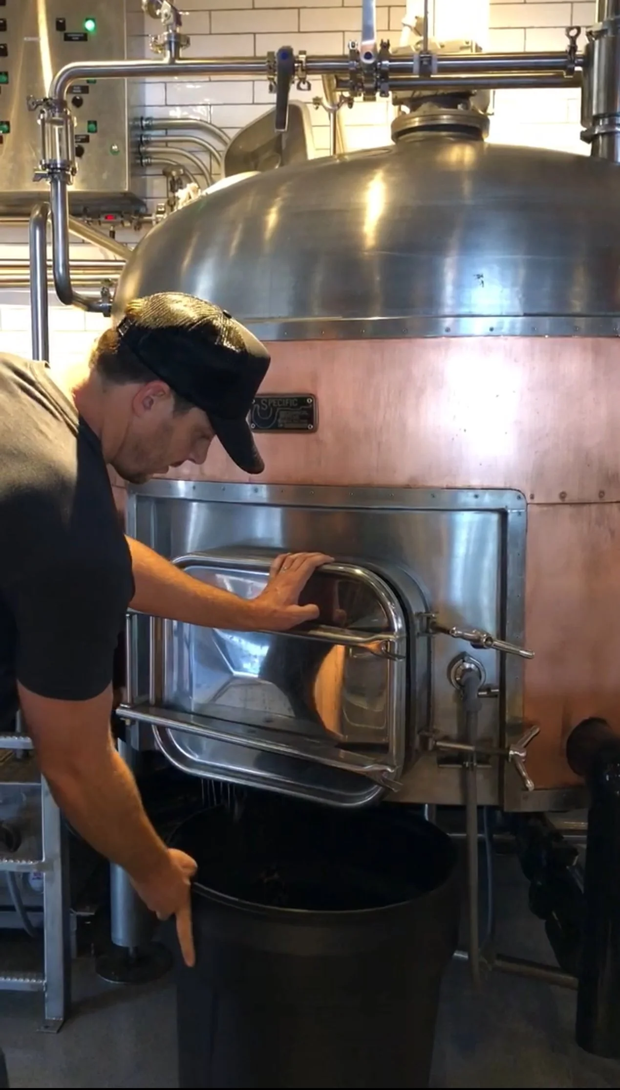 A person opening the door of a large, industrial oven or kiln in a commercial kitchen or bakery.