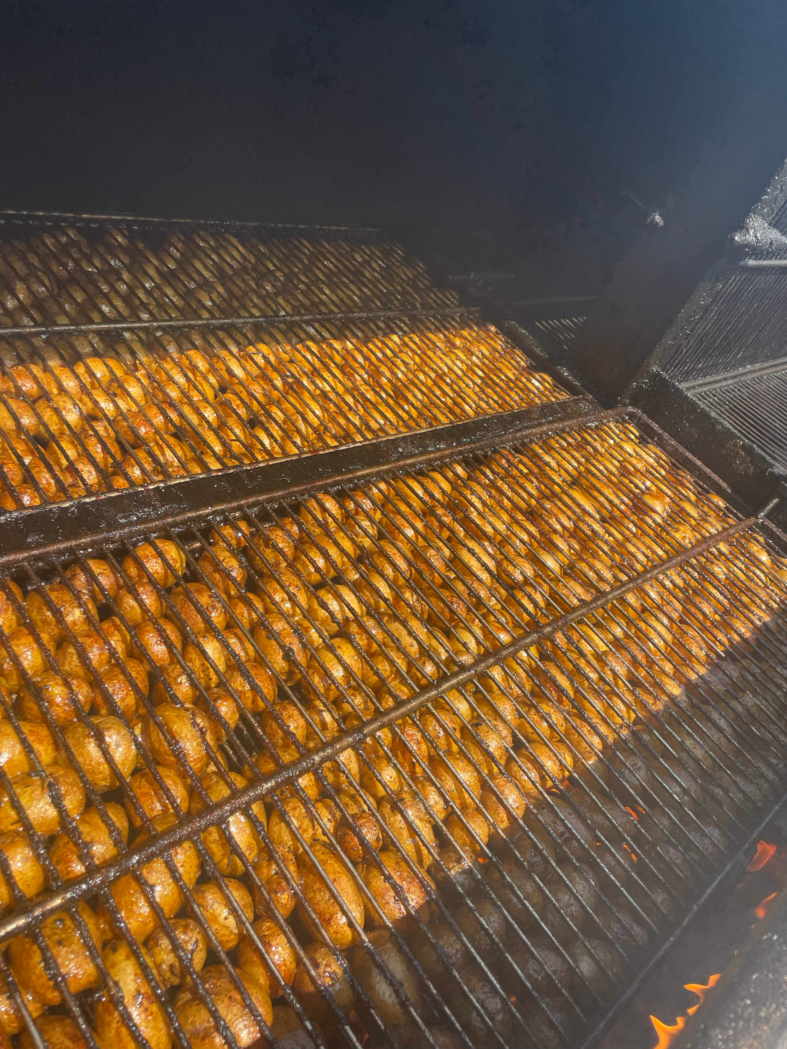Two racks of grilling chicken wings in a barbecue grill by Kings BBQ in Indiana.