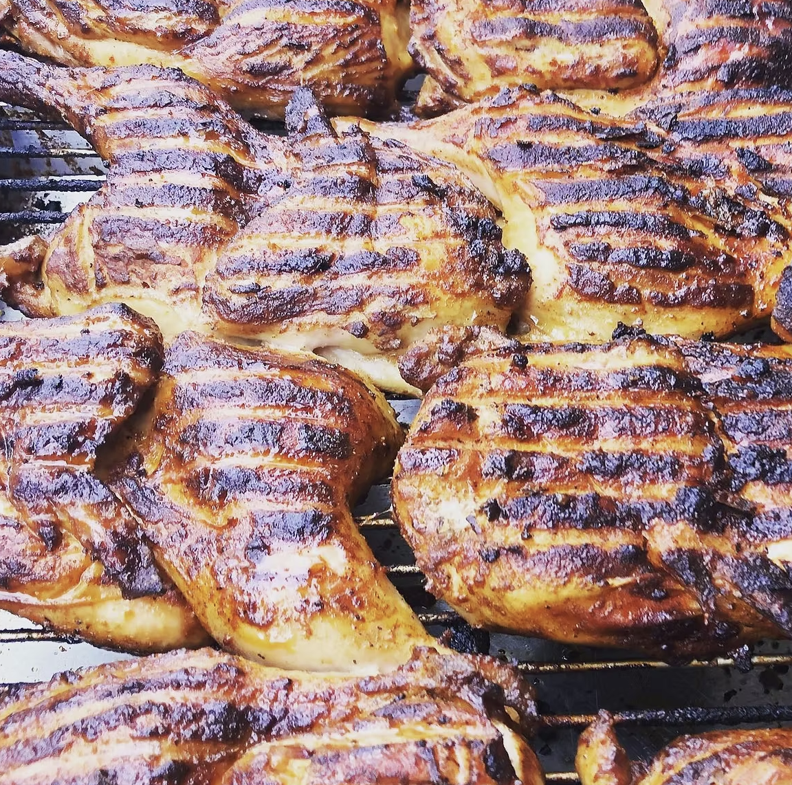 Close-up of grilled chicken thighs with char marks on a wire rack.