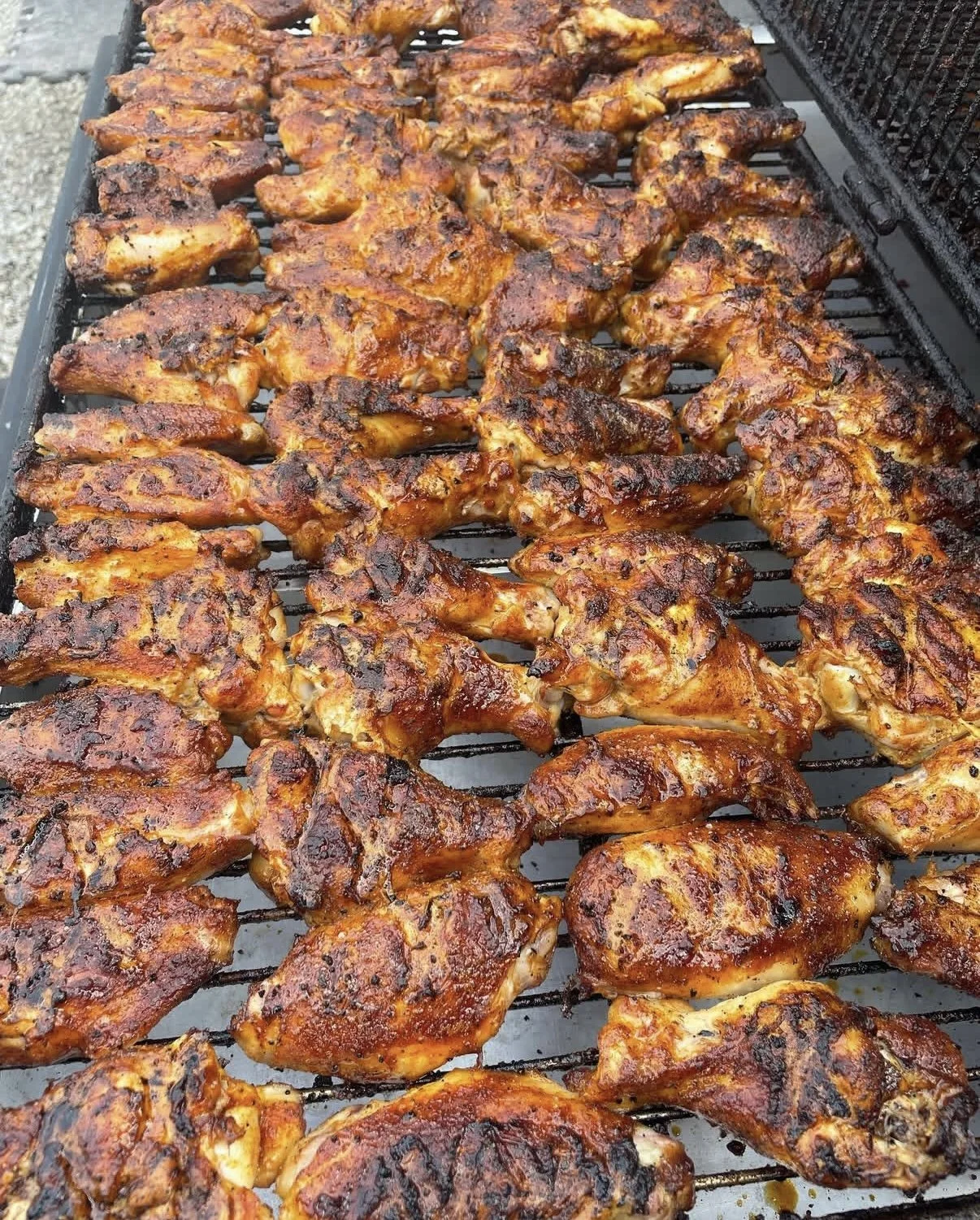 Grilled chicken drumsticks with browned, charred coating on a grill.