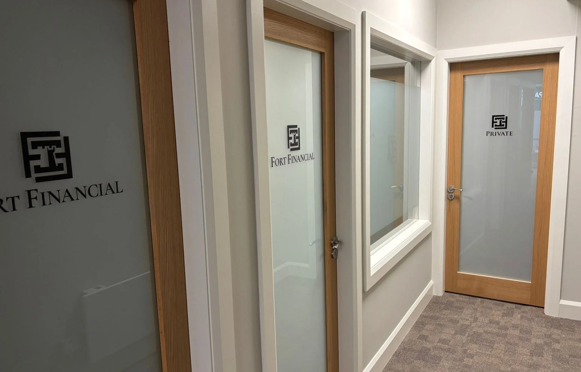 Office hallway with frosted glass doors labeled 'Fort Financial' and 'Private' in a professional building.