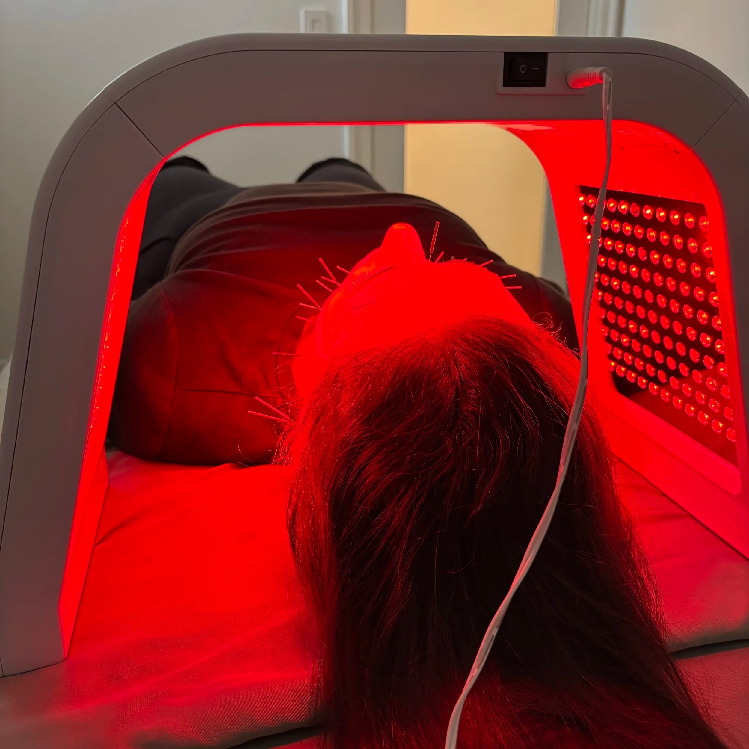 Person’s head inside a red laser scanner device with a white cord running from the device.