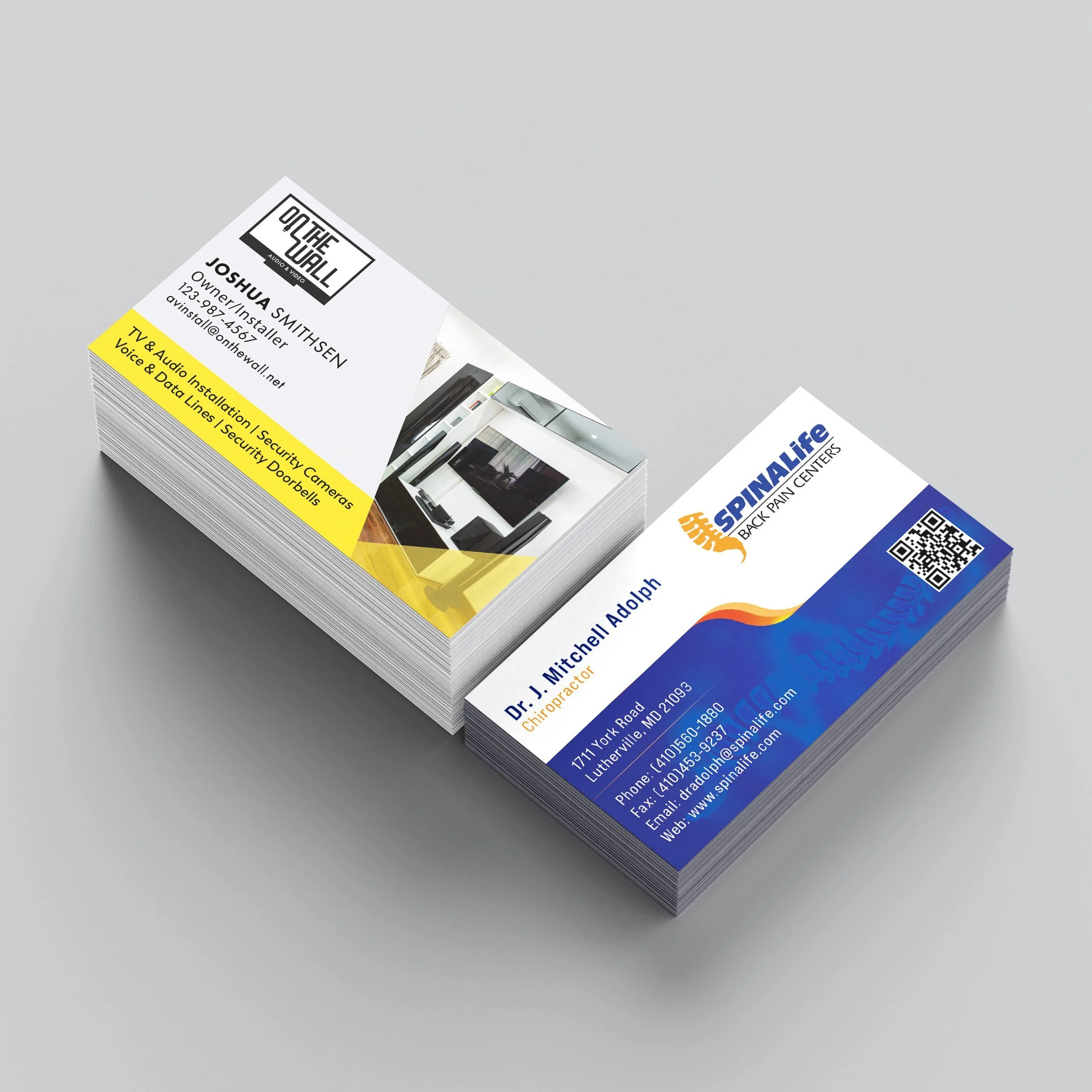 Stack of two business cards, one for Dr. J. Mitchell Adolph and the other for SpineLife Back Pain Centers, on a light gray surface.