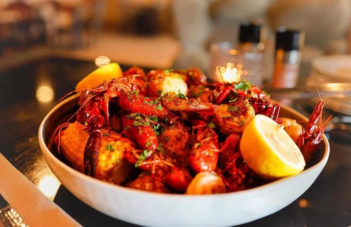 Seafood boil with crawfish, shrimp, and corn served with lemon wedges.