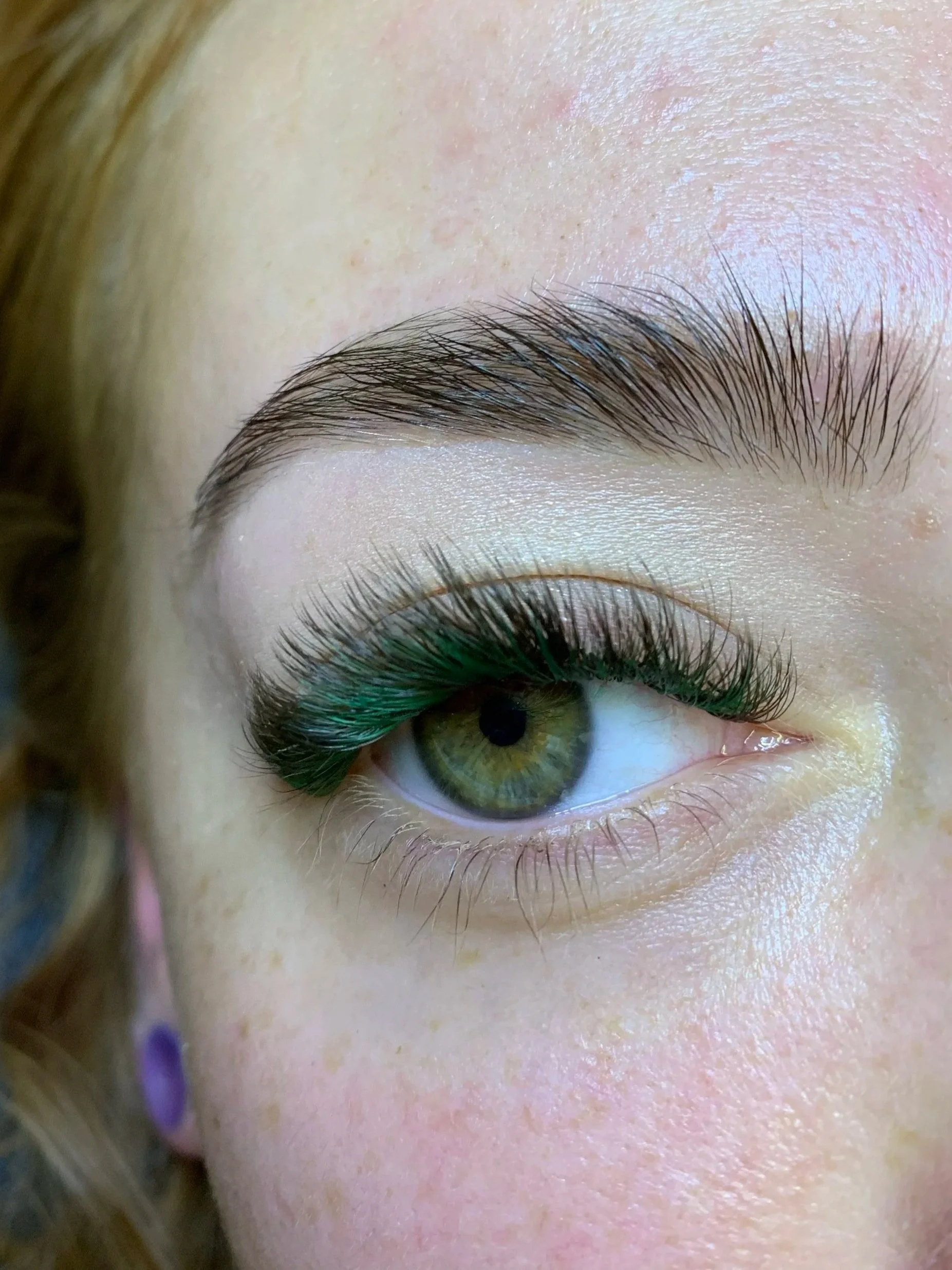 Close-up of a person's eye showing detailed eyelashes, eyebrow, and part of the skin and forehead.