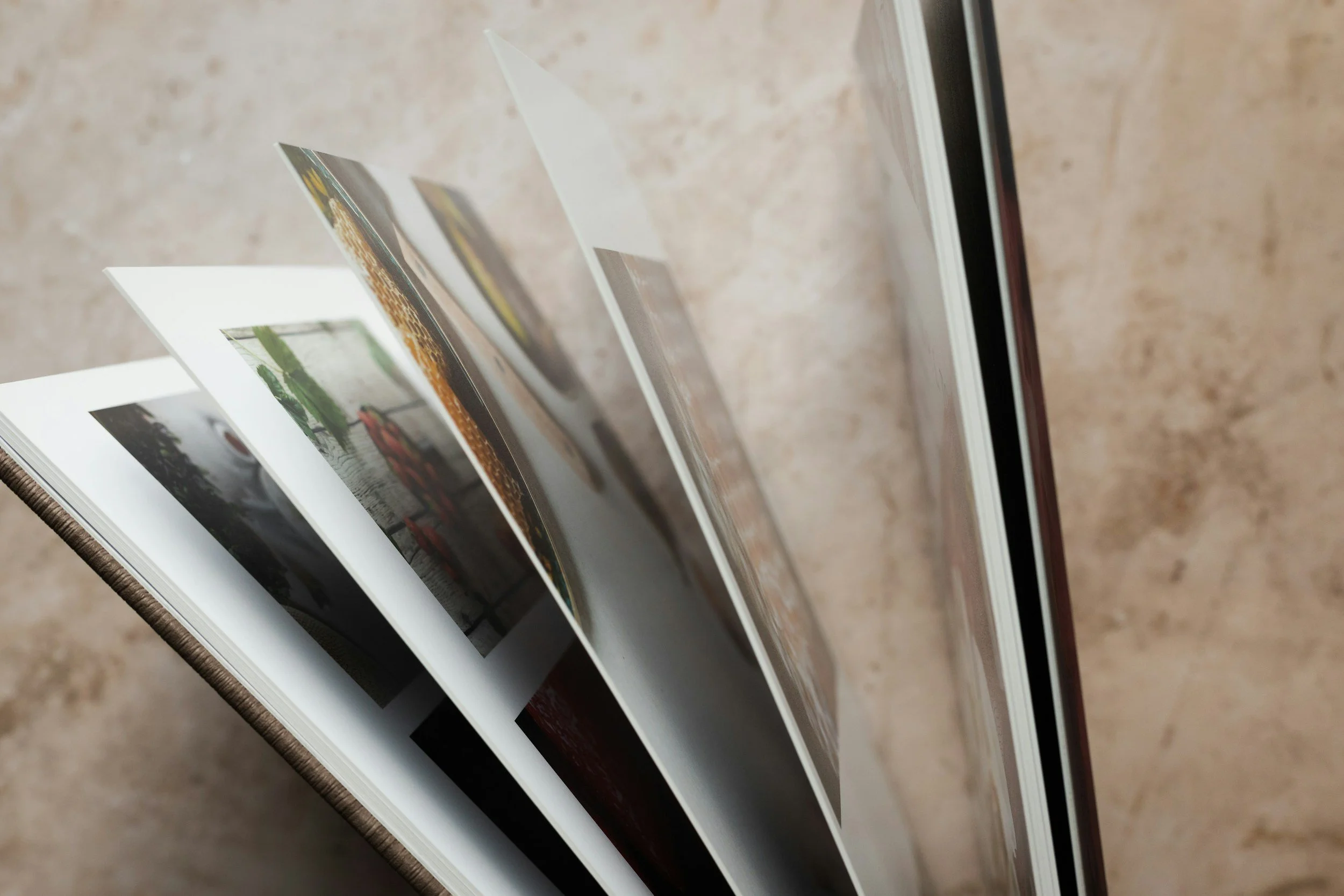 Open photo book displaying multiple pages with photographs on a beige surface.