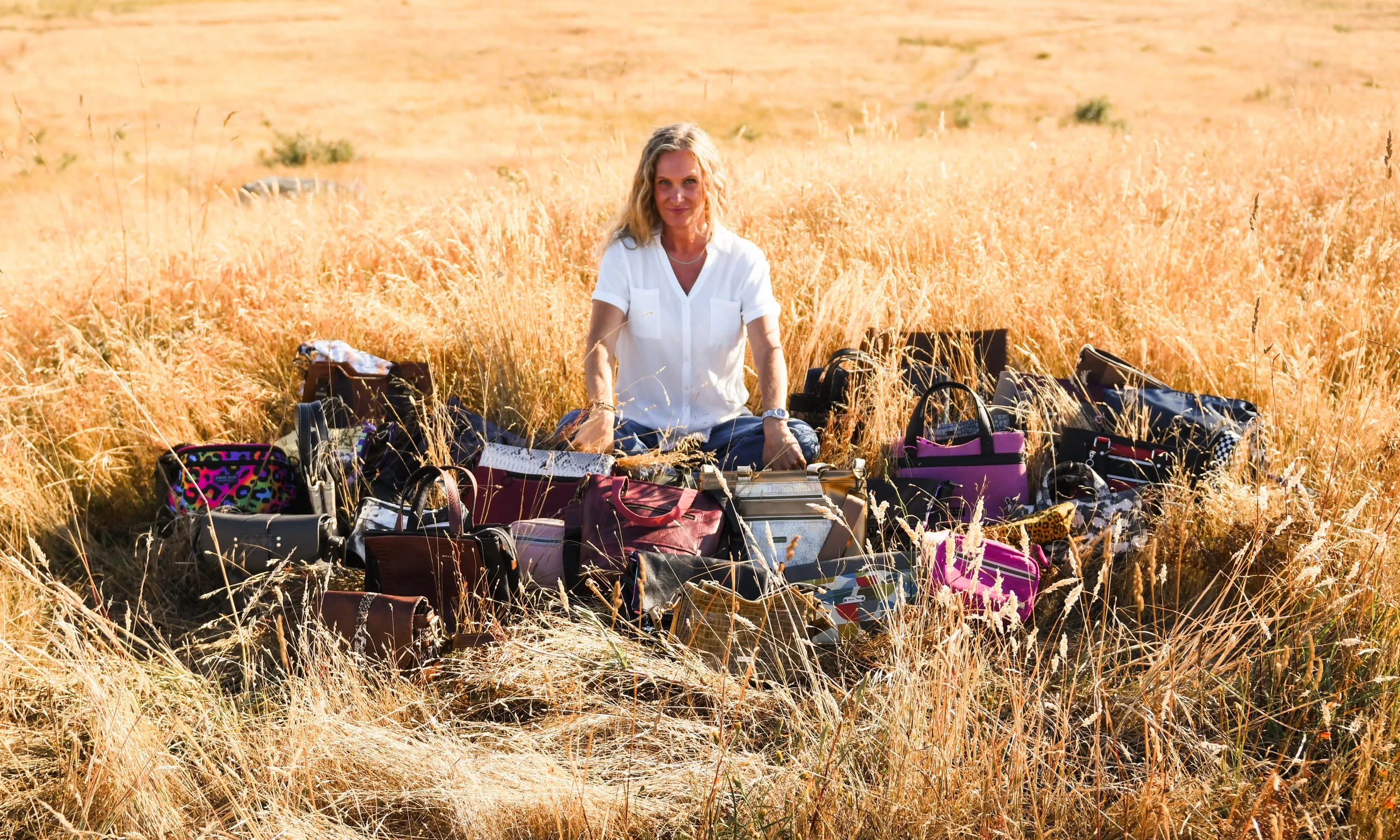Stacey sitting in a grass field with the chaos collection bags in front of her