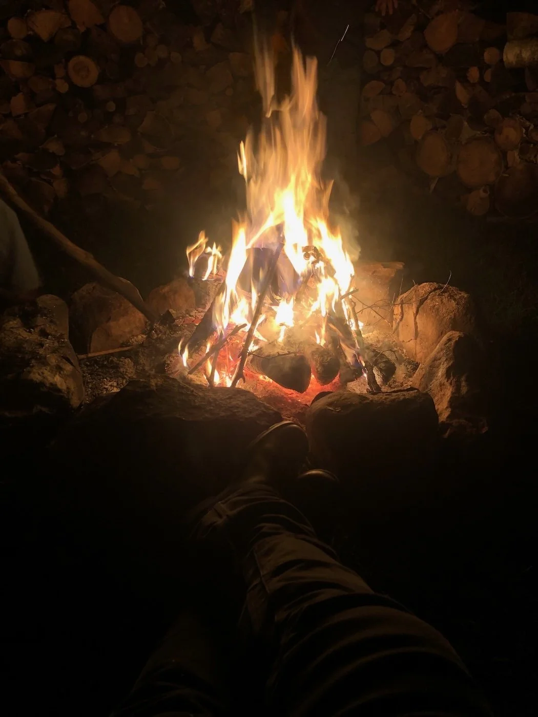 A close up on a roaring camp fire at night glowing embers and flame.