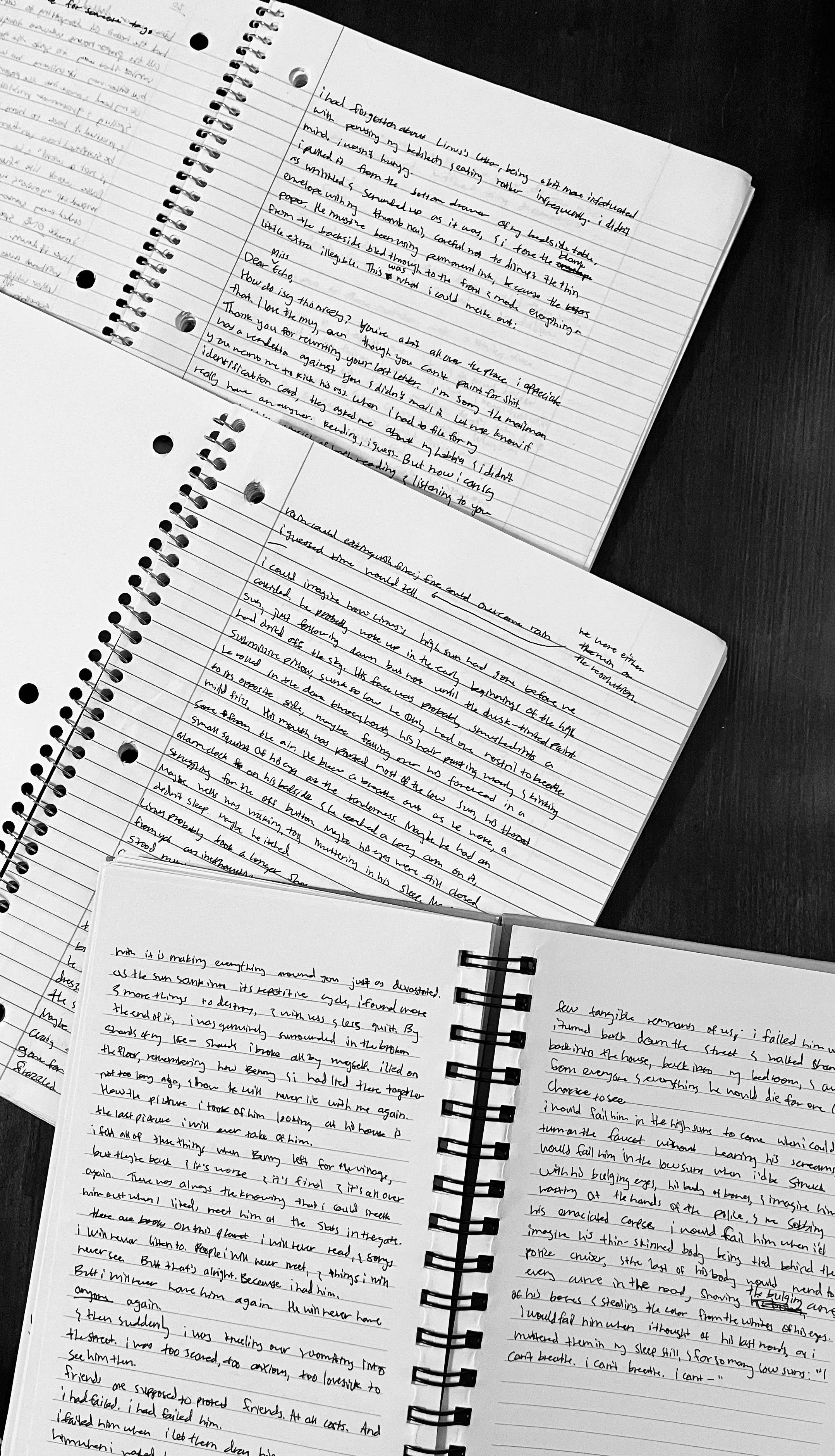 Three spiral notebooks with handwritten notes on lined paper lying on a dark surface.