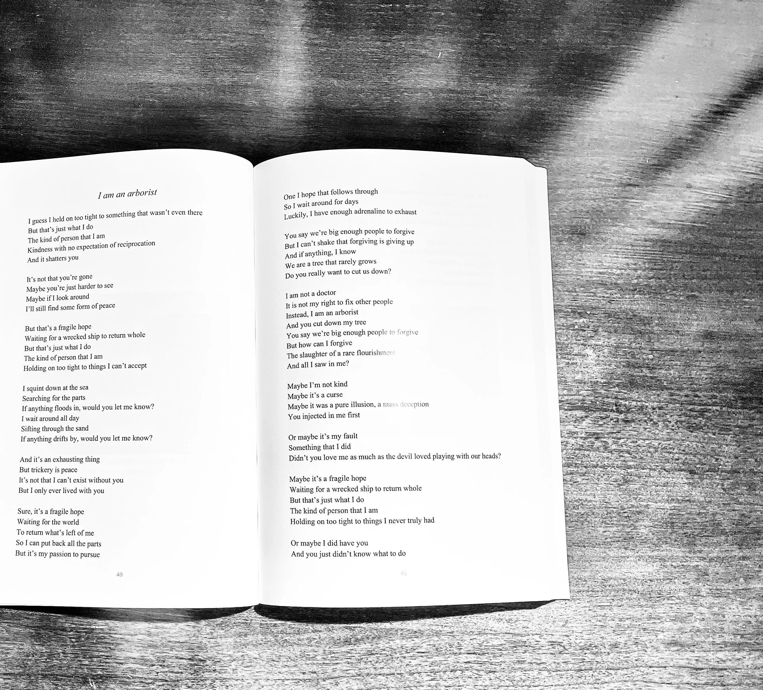 Open book on a wooden surface, displaying a poem titled "I am an arborist."