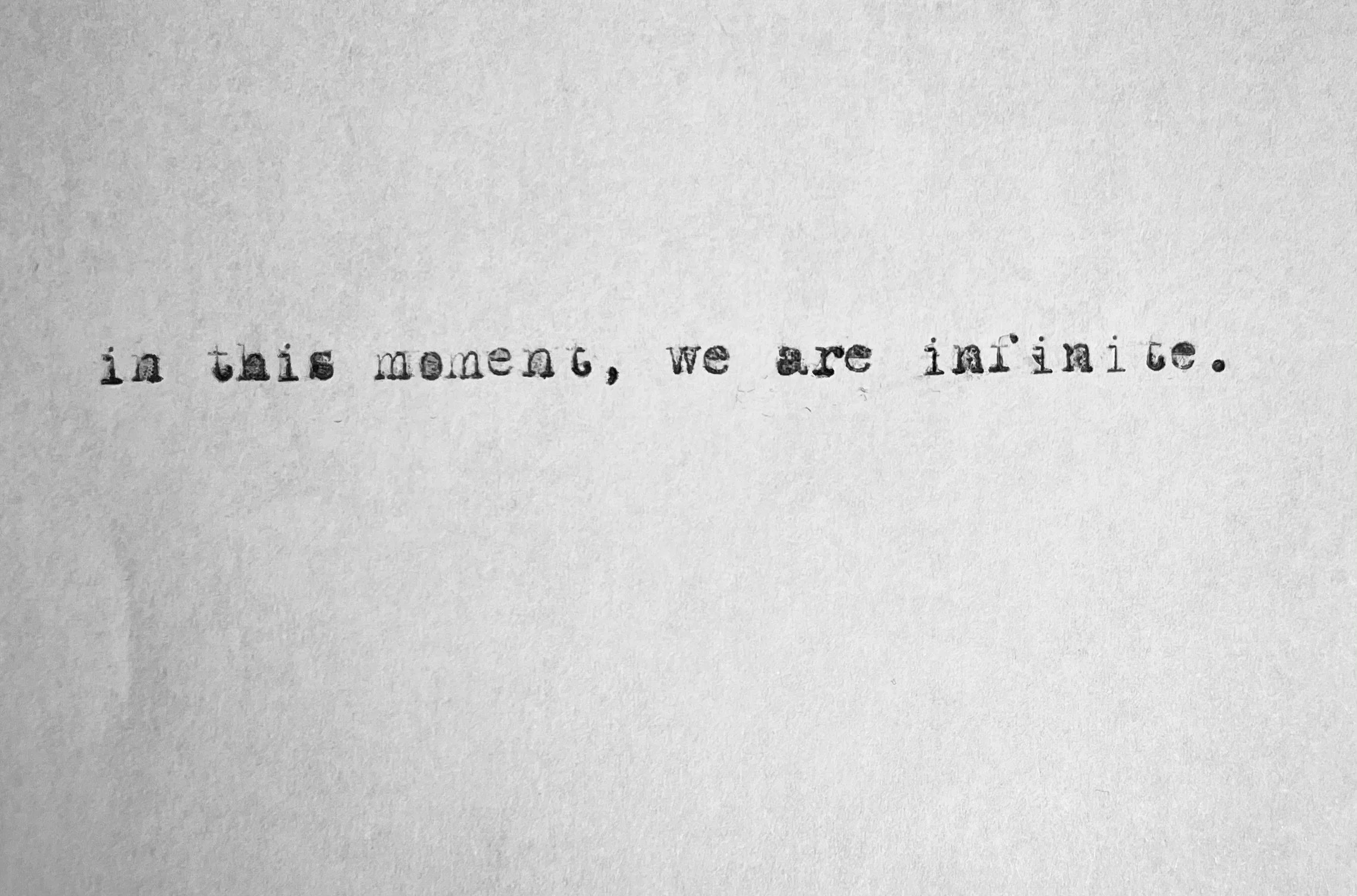 Typewritten quote on white paper reads, "in this moment, we are infinite."