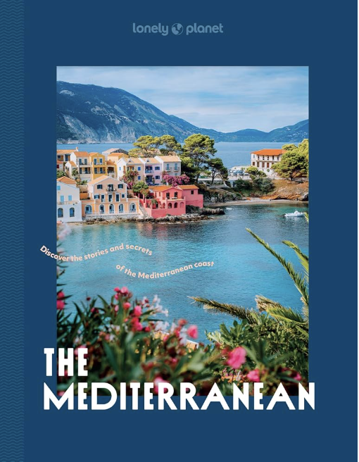 Cover of a travel brochure featuring colorful houses by a Mediterranean seaside, with mountains in the background and pink flowers in the foreground. The brochure is titled "The Mediterranean" by Lonely Planet.