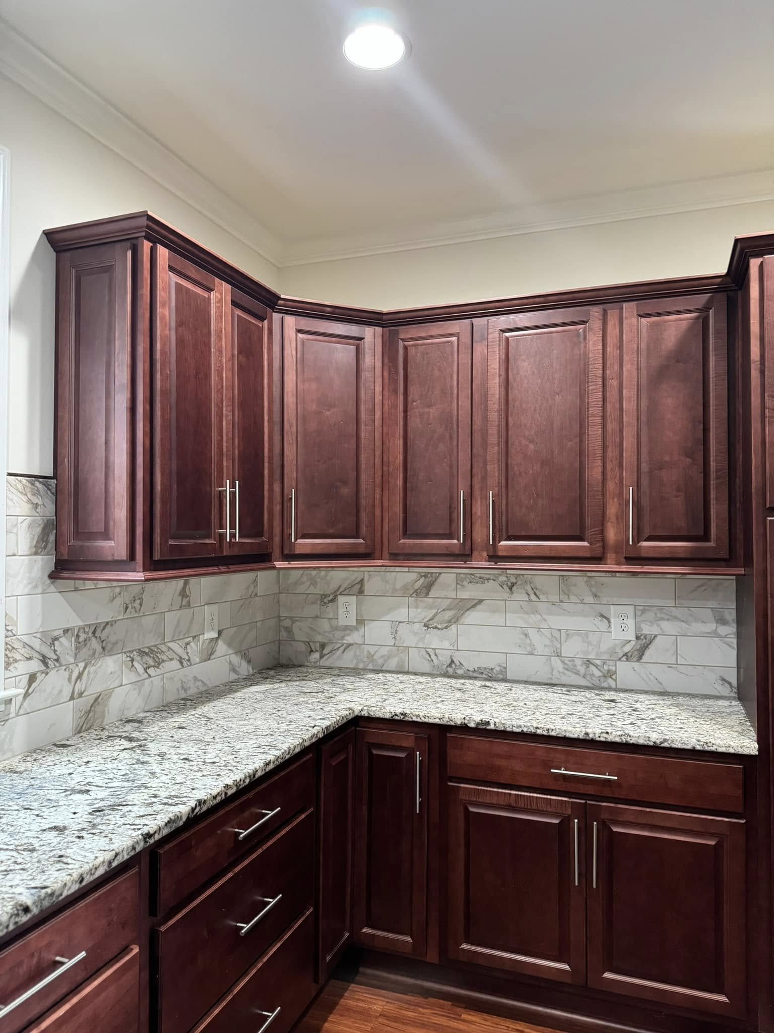 Kitchen with cherry wood cabinets, granite countertops, and a marble backsplash.