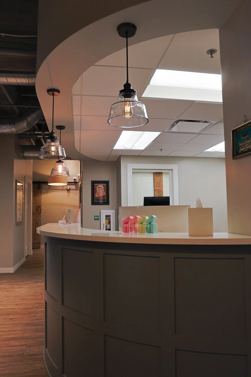 Modern reception desk area with hanging pendant lights and a colorful display of small gift boxes.