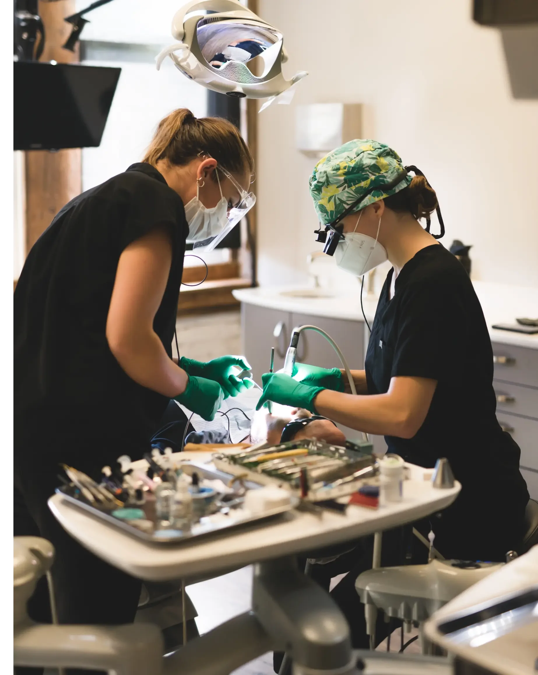 Two dental professionals performing a dental procedure on a patient in a dental clinic.