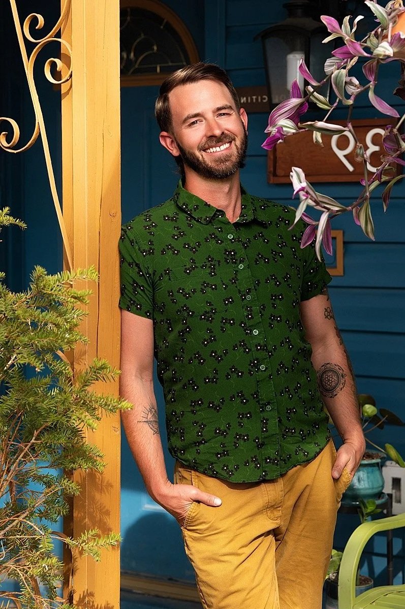 Portrait of Licensed Professional Counselor, Adam Stanford, posing in Colorado. He wears a green shirt and mustard-colored pants, and white sneakers.