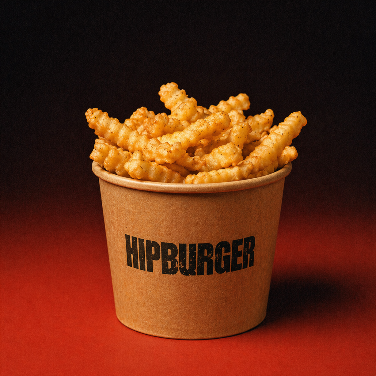 Crinkle-cut French fries in a brown cup with the word 'HIPBURGER' printed on it, against a dark background.