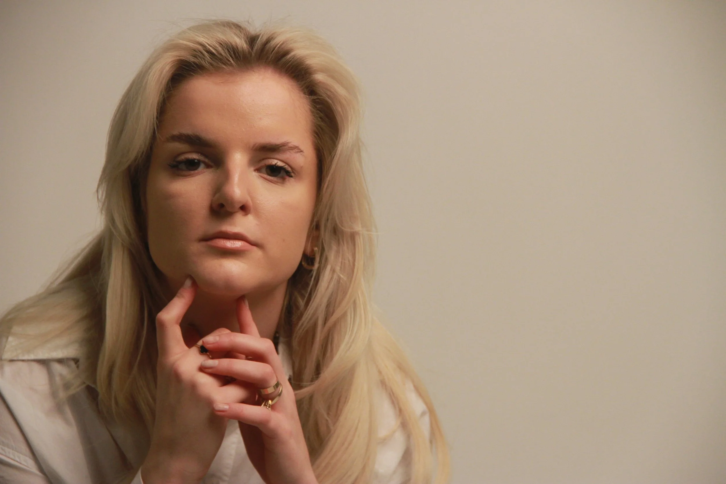 Studio portrait of Gjeneta with hands under chin, direct gaze and soft directional lighting.