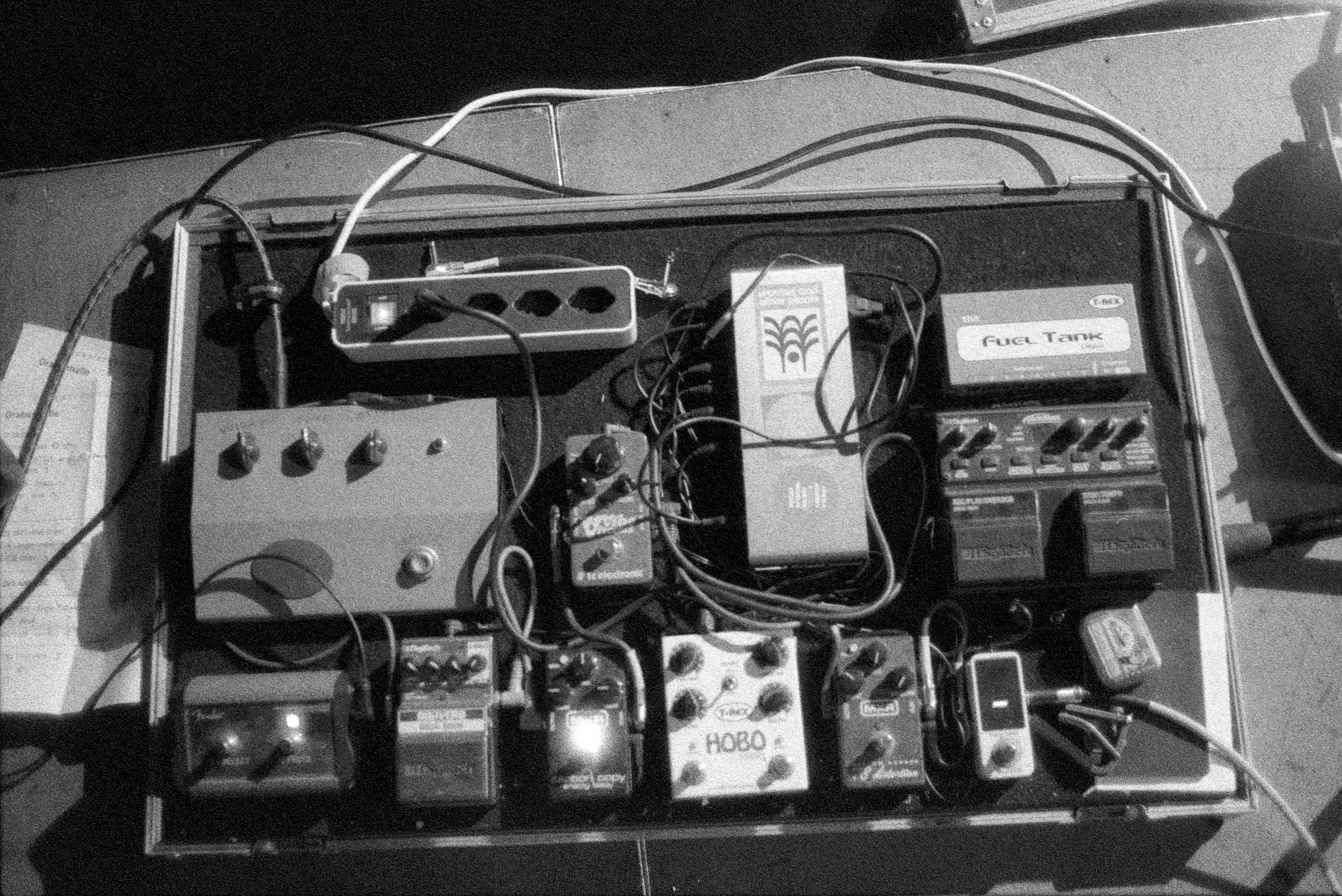 Guitar pedalboard and cables on stage floor during soundcheck.