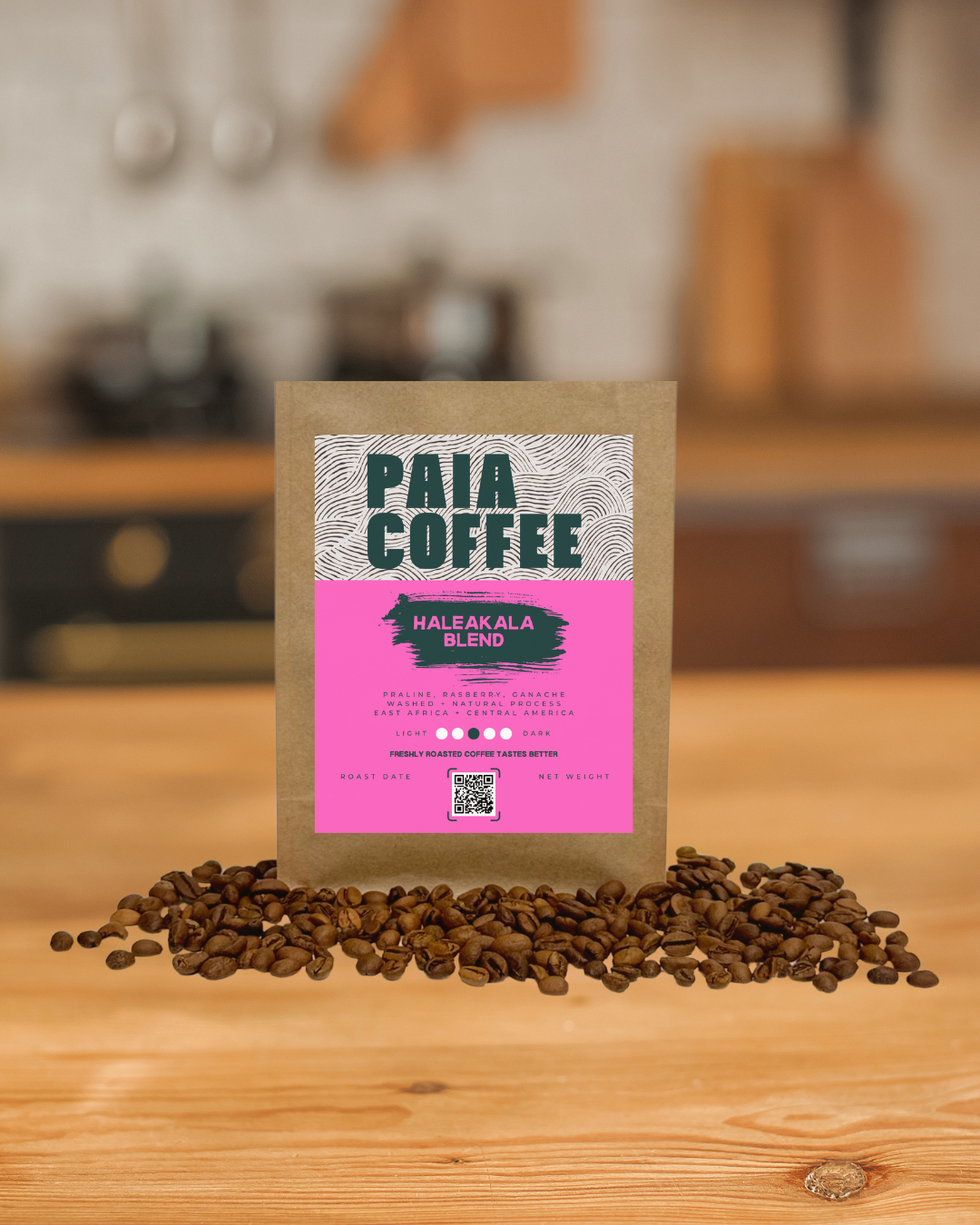 A package of Paia Coffee Haleakala Blend surrounded by coffee beans on a wooden surface, with a blurred kitchen background.