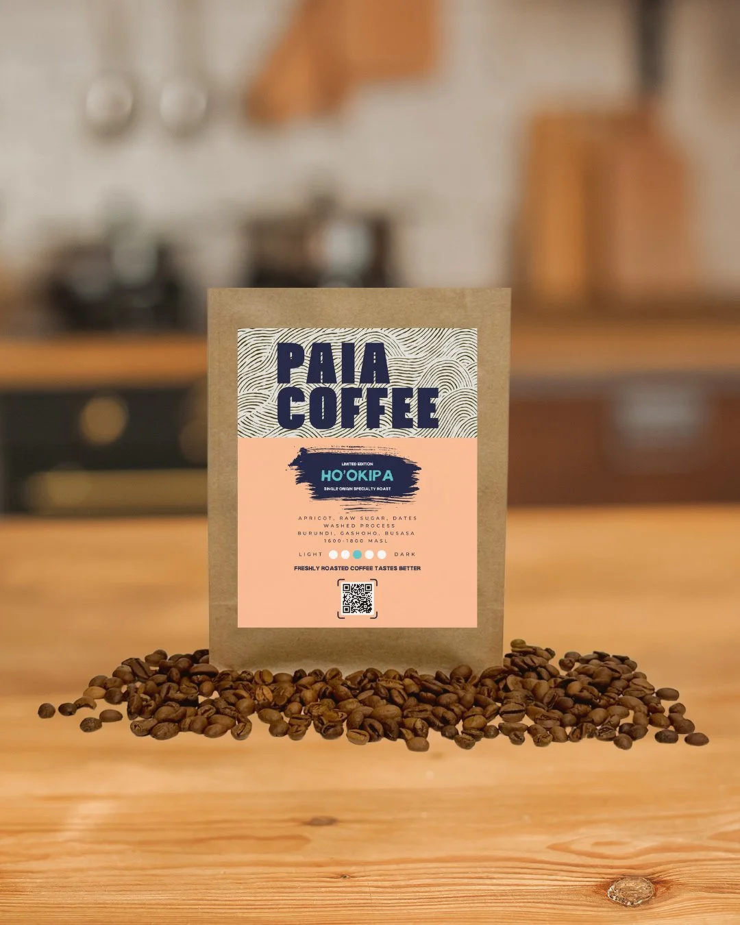A brown paper bag of Paia Coffee on a wooden surface with scattered coffee beans in front of it, in a kitchen setting