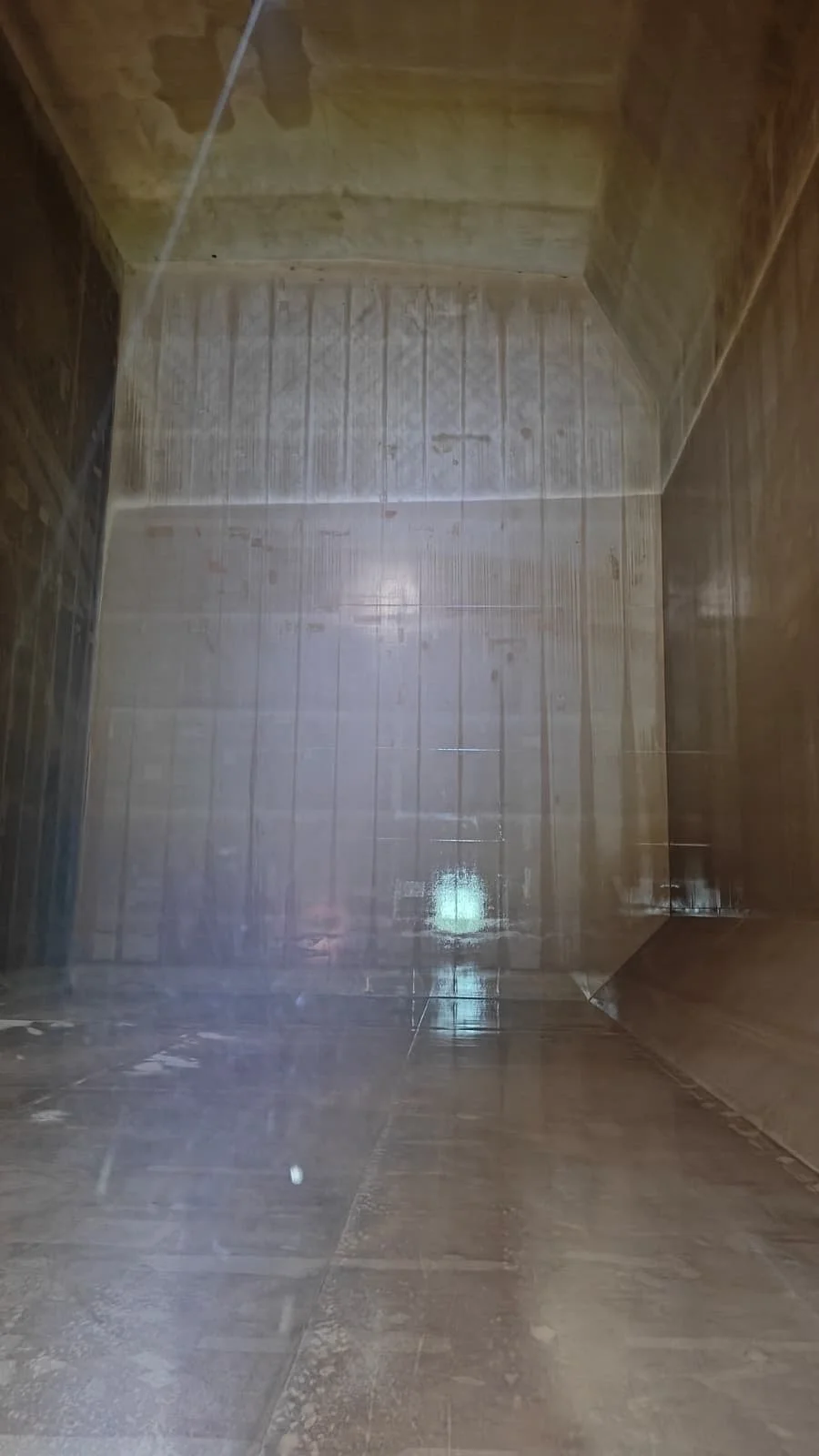 View of an empty, tiled shower stall with brown tiles on the walls and floor, seen from inside.