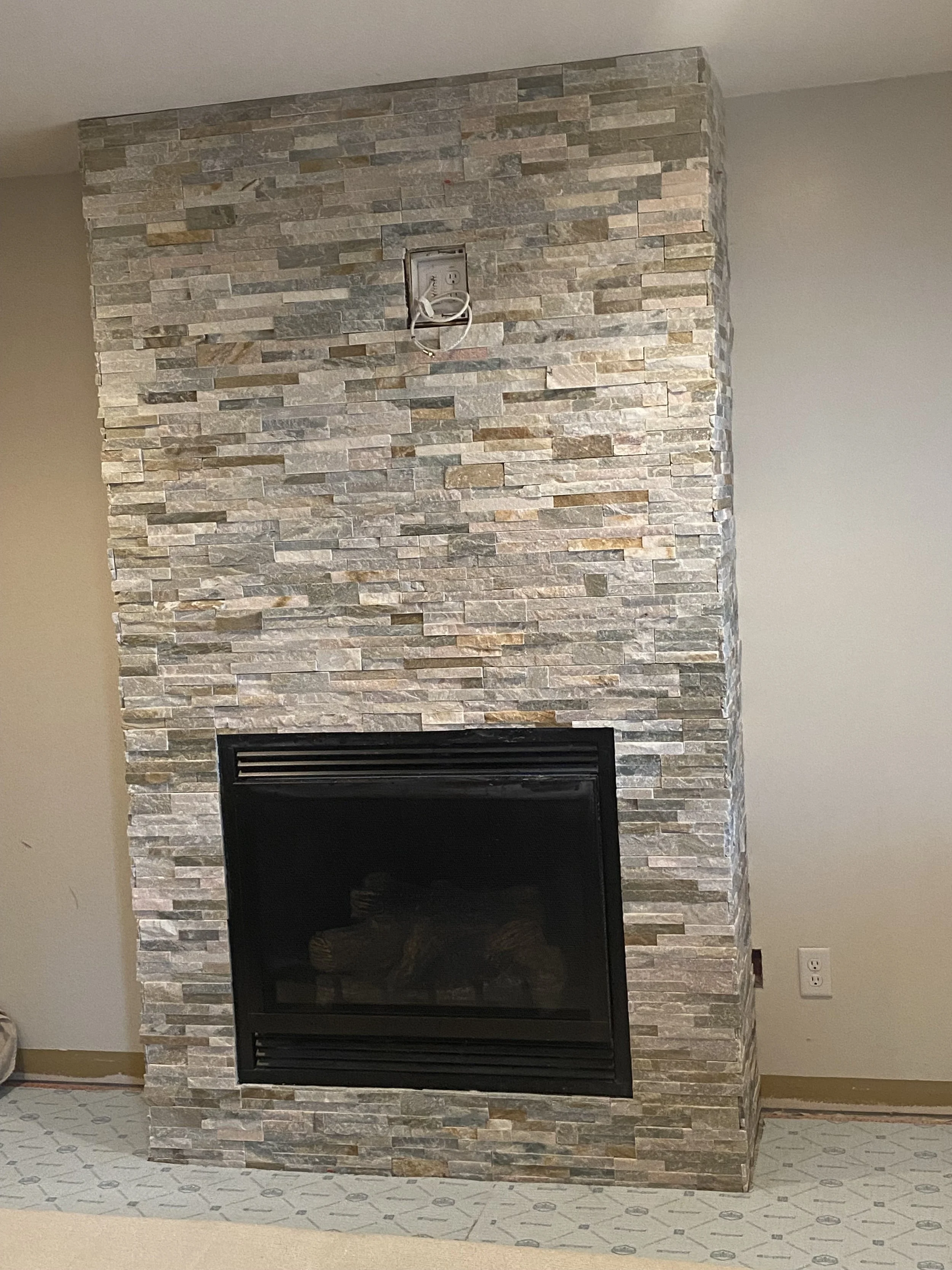 Fireplace with a stone veneer surround in a room under construction or renovation.