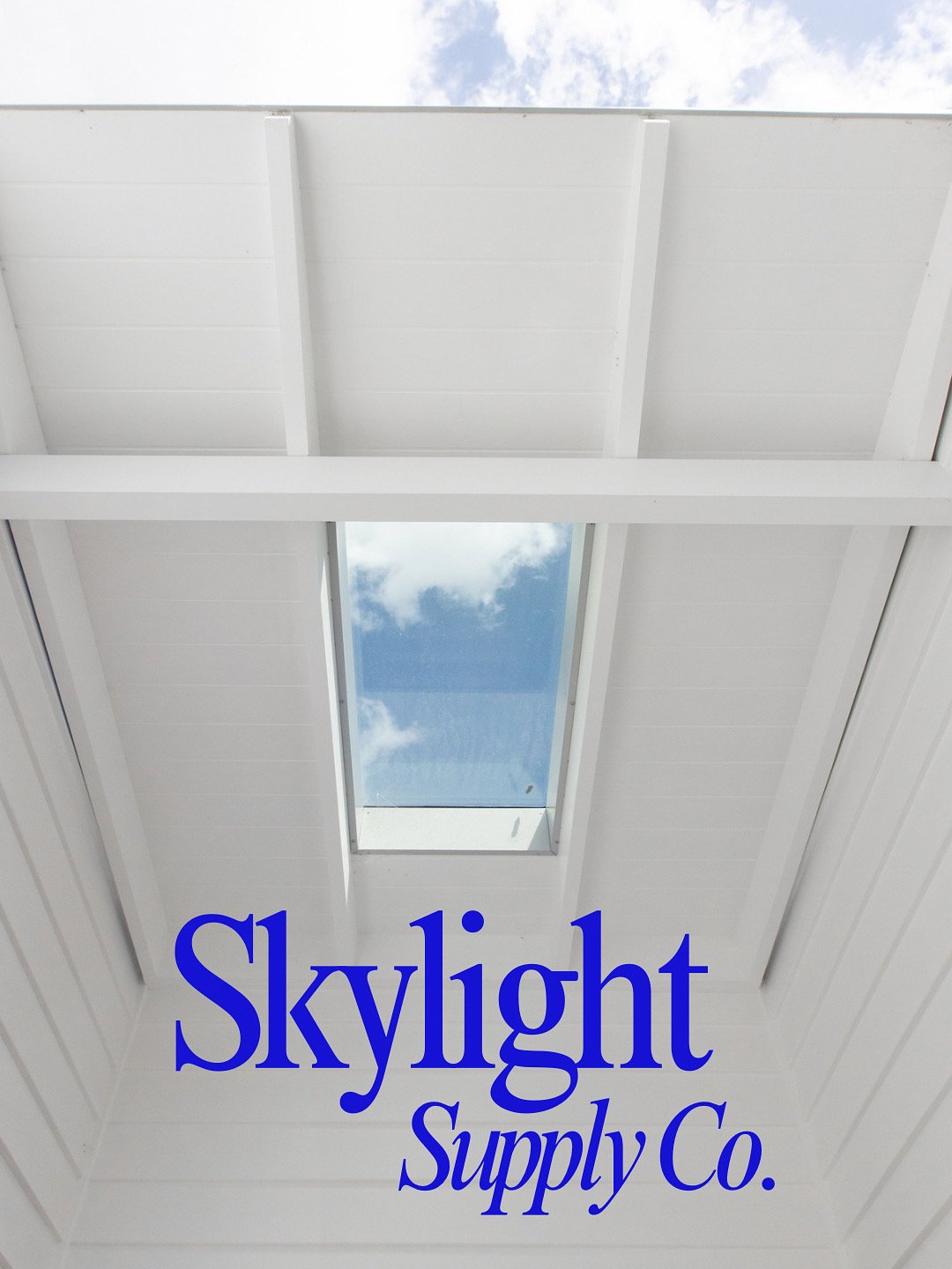 White ceiling with skylight allowing natural light and view of blue sky with clouds.