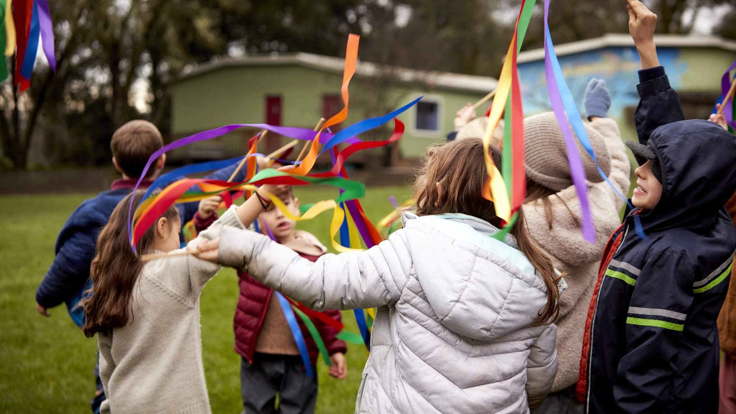 Children outdoors playing with colorful ribbons during a festive event at Waldorf School.