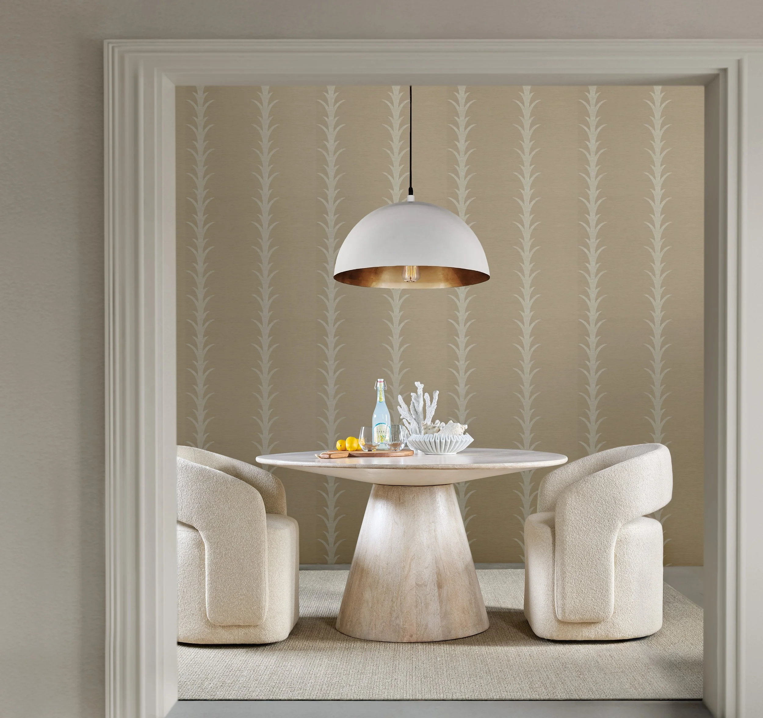 Contemporary dining nook featuring a round pedestal table, curved boucle dining chairs, a white dome pendant light, and neutral patterned wallpaper in soft beige tones.