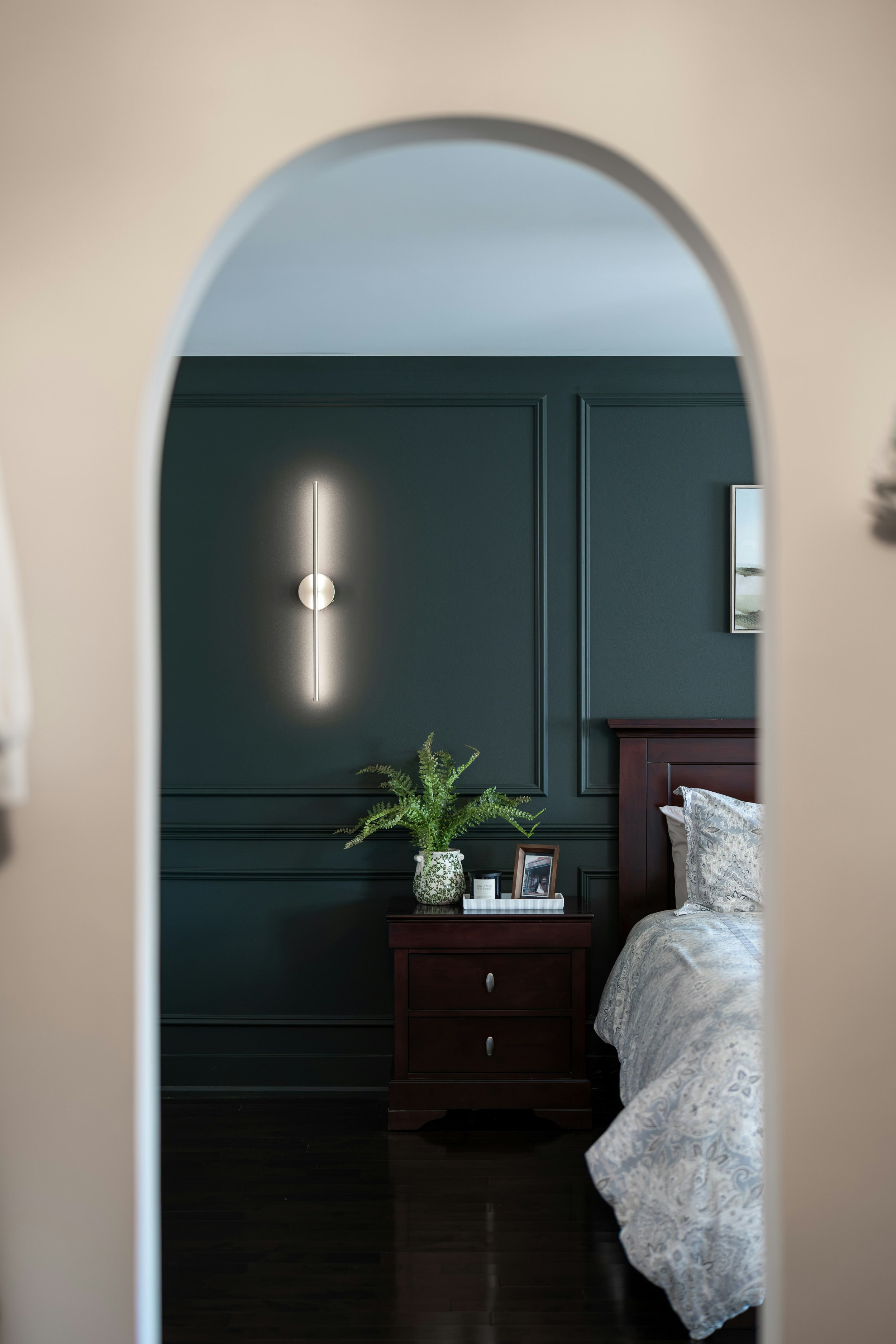Painted wall panelling accent wall framing a bed and bedside lighting.