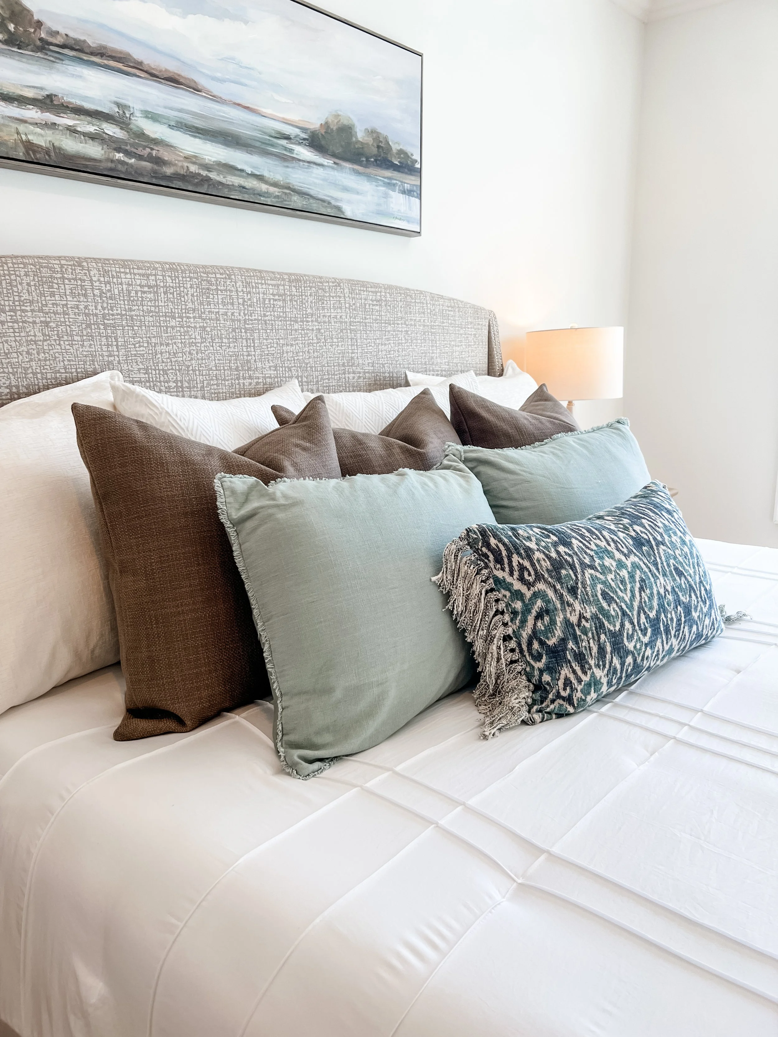 Coastal inspired pillow arrangment on bed