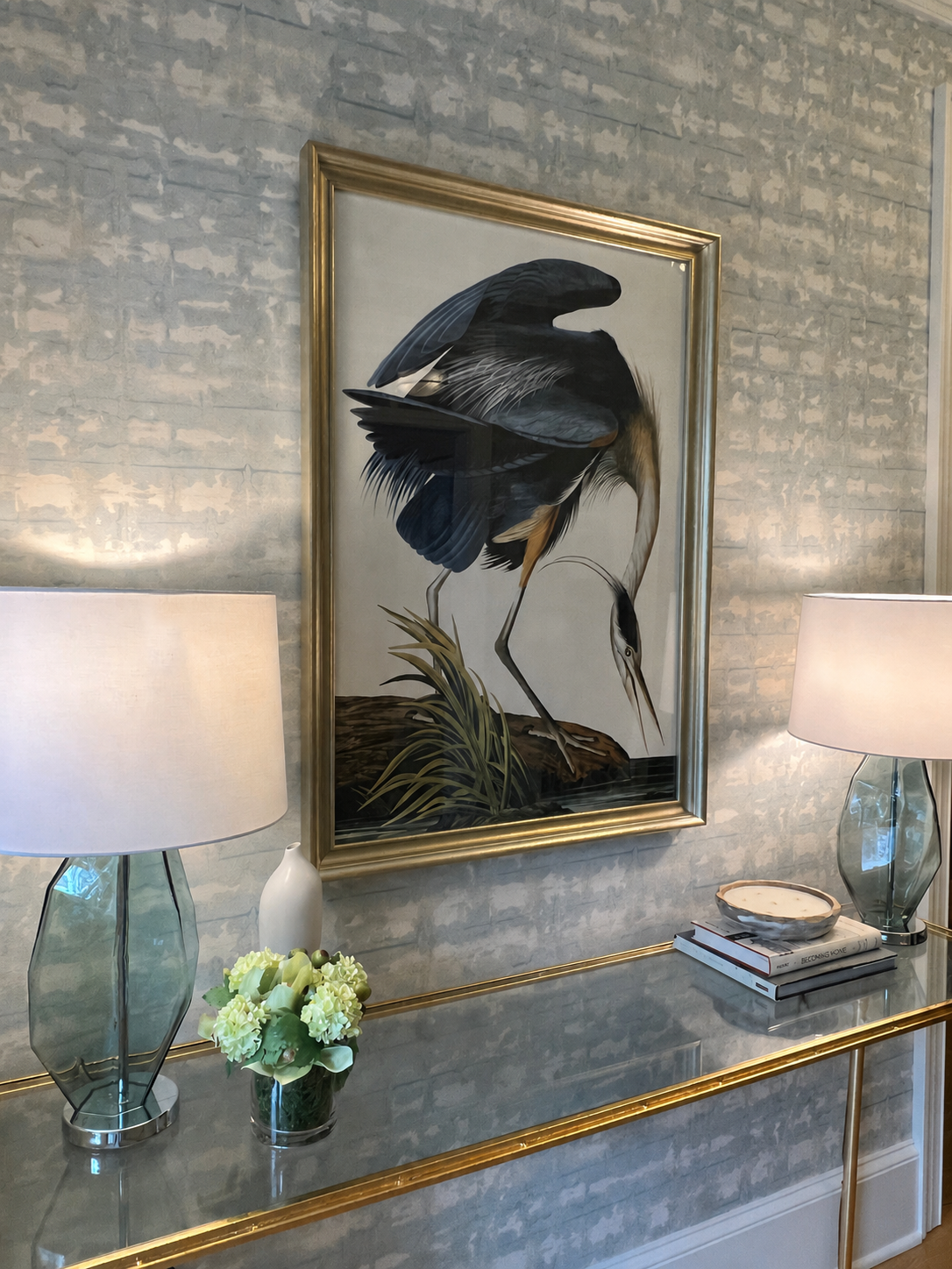 gold console table with blue lamps, heron artwork and light blue wallpaper