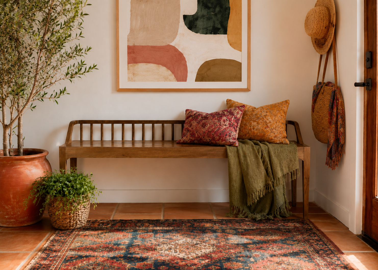 Warm, bohemian-style foyer featuring a natural wood spindle-back bench with textured neutral pillows and a draped fringed throw.