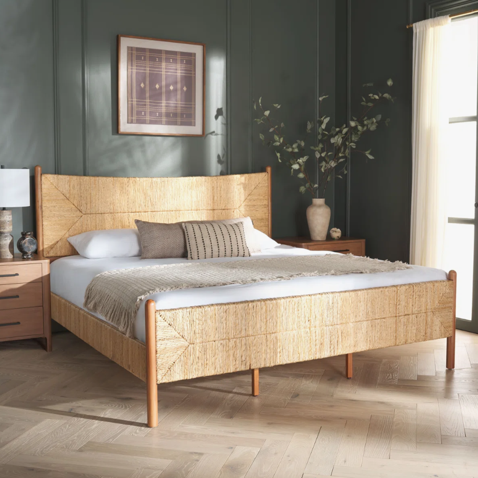 Boho bedroom featuring a woven banana stem bed, moody green walls, natural textures, and warm wood furniture.