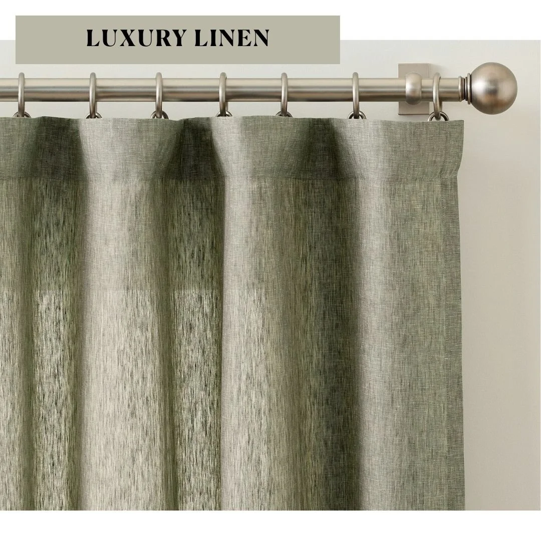 Sage green Belgian flax linen curtain panels with soft natural texture hanging from a brass curtain rod with rings.