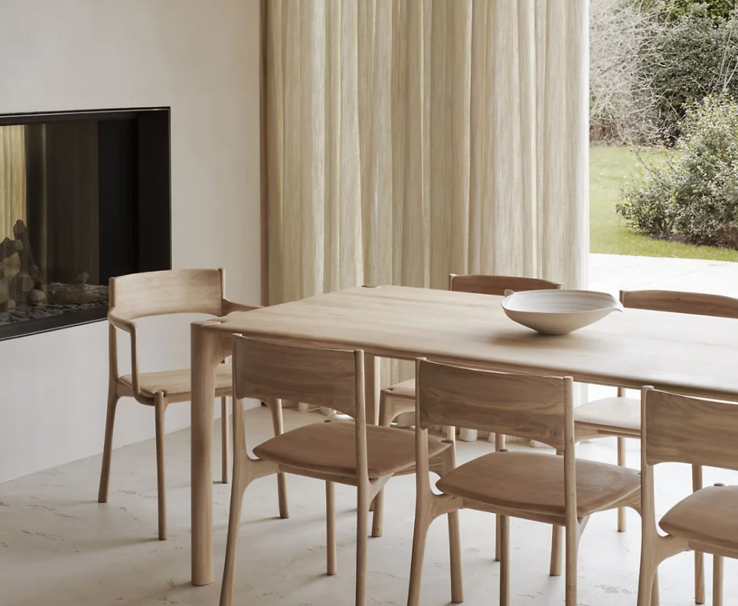 Ethnicraft PI dining chairs surrounding a solid wood dining table in a Scandinavian-inspired dining room featuring clean lines, natural oak finishes, floor-to-ceiling linen drapery, and a warm minimalist aesthetic.