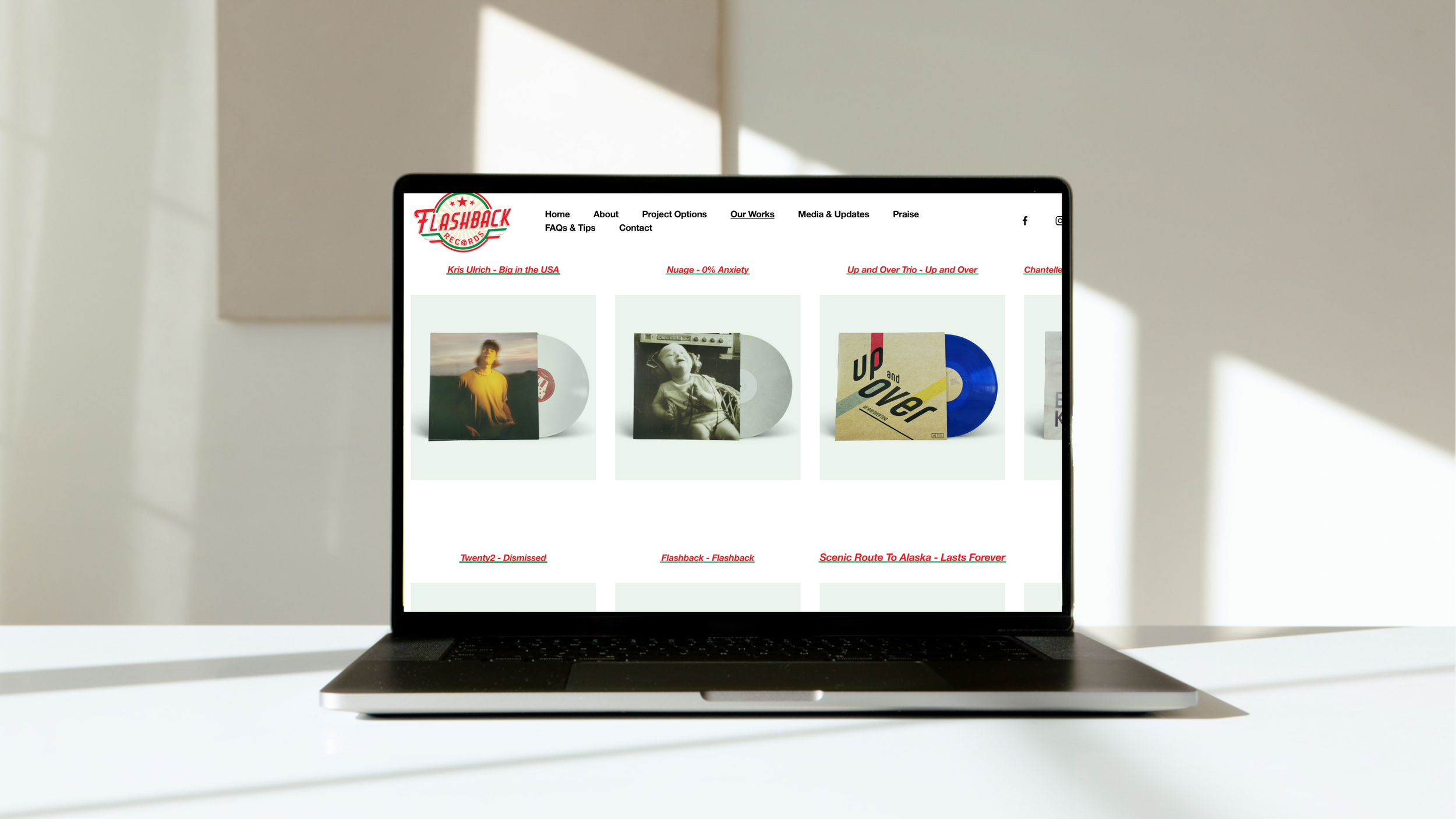 Laptop on a white table displaying a website with a music record label called 'Flashback Records,' showing various album covers and links in the navigation menu.