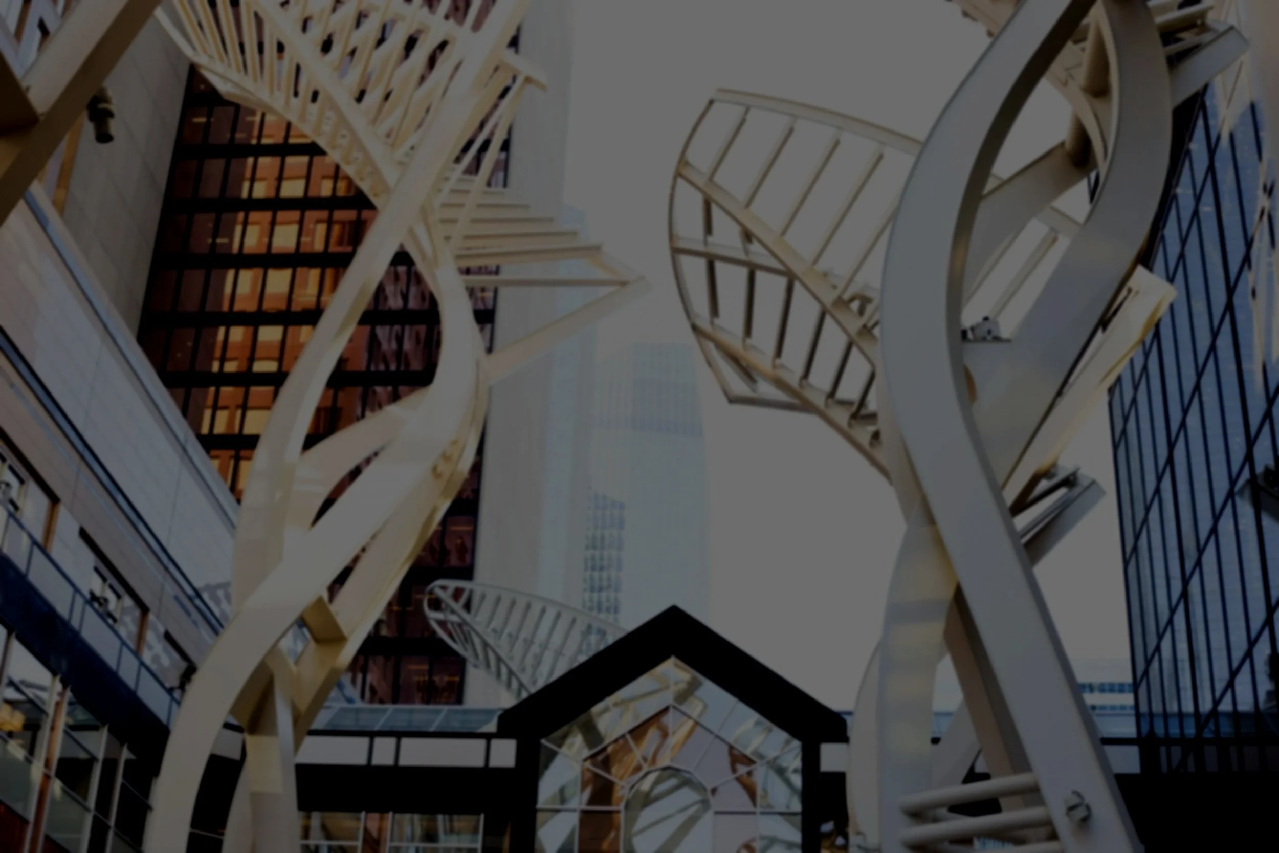 Modern urban architectural detail with intertwined white spiral and straight staircases among glass buildings.