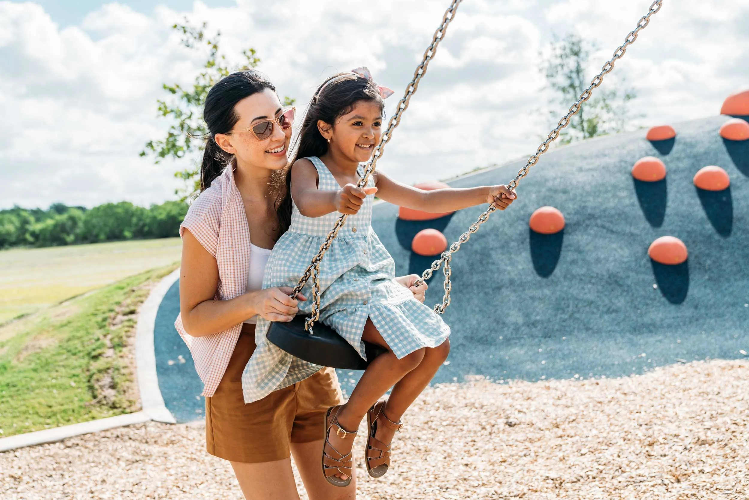 Woman-Pushing-Girl-on-Swing-in-Park.jpg