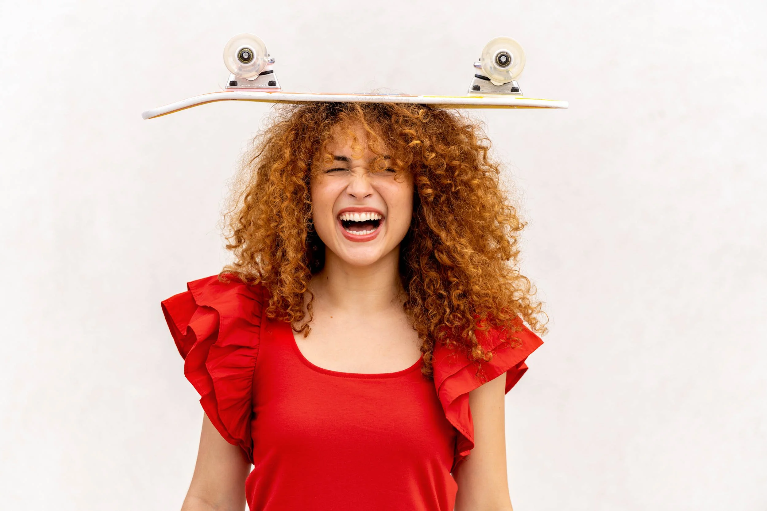 Smiling-Woman-Balancing-Skateboard-on-Head.jpg