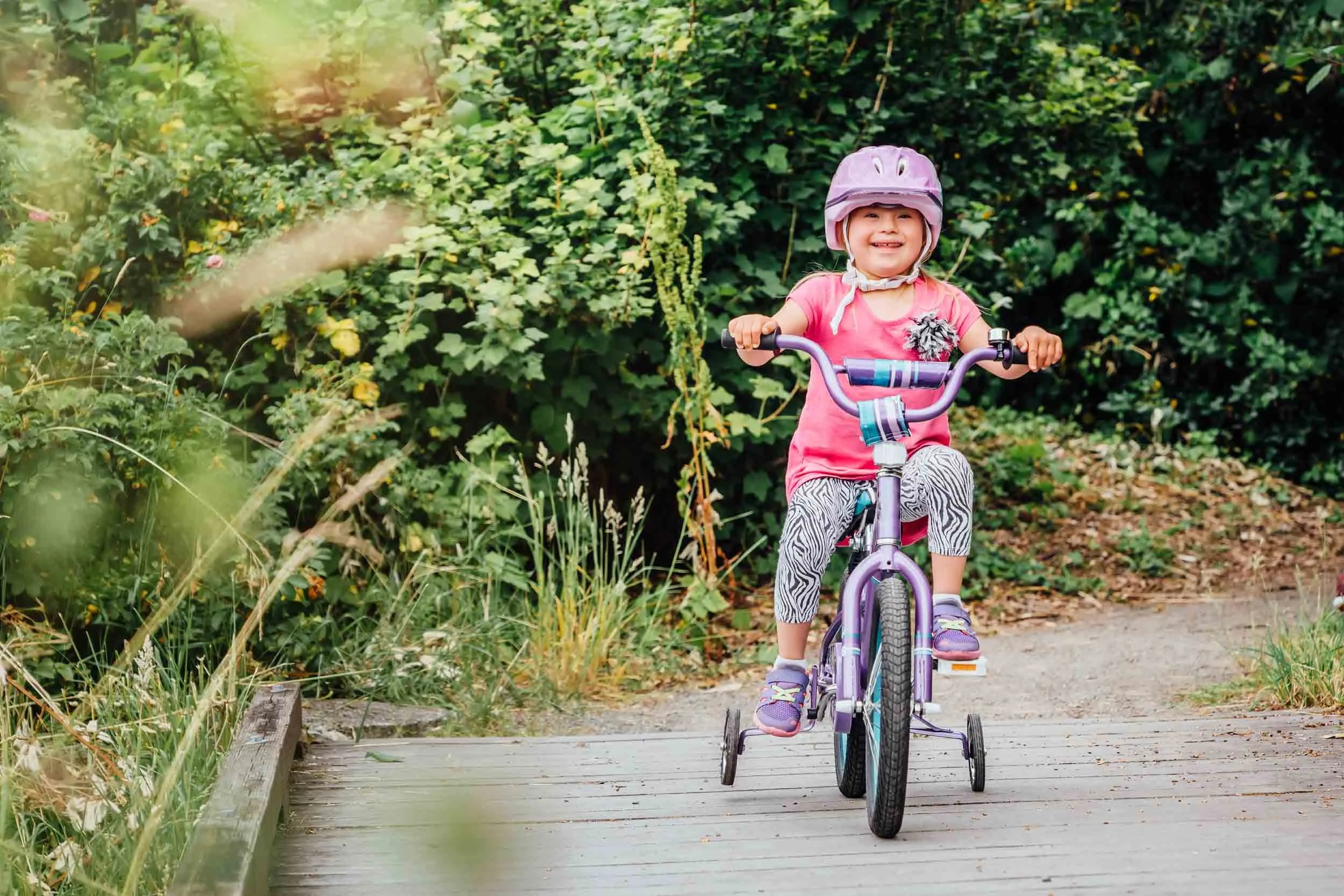 Downs-Syndrome-Child-Biking-on-Wooden-Path.jpg