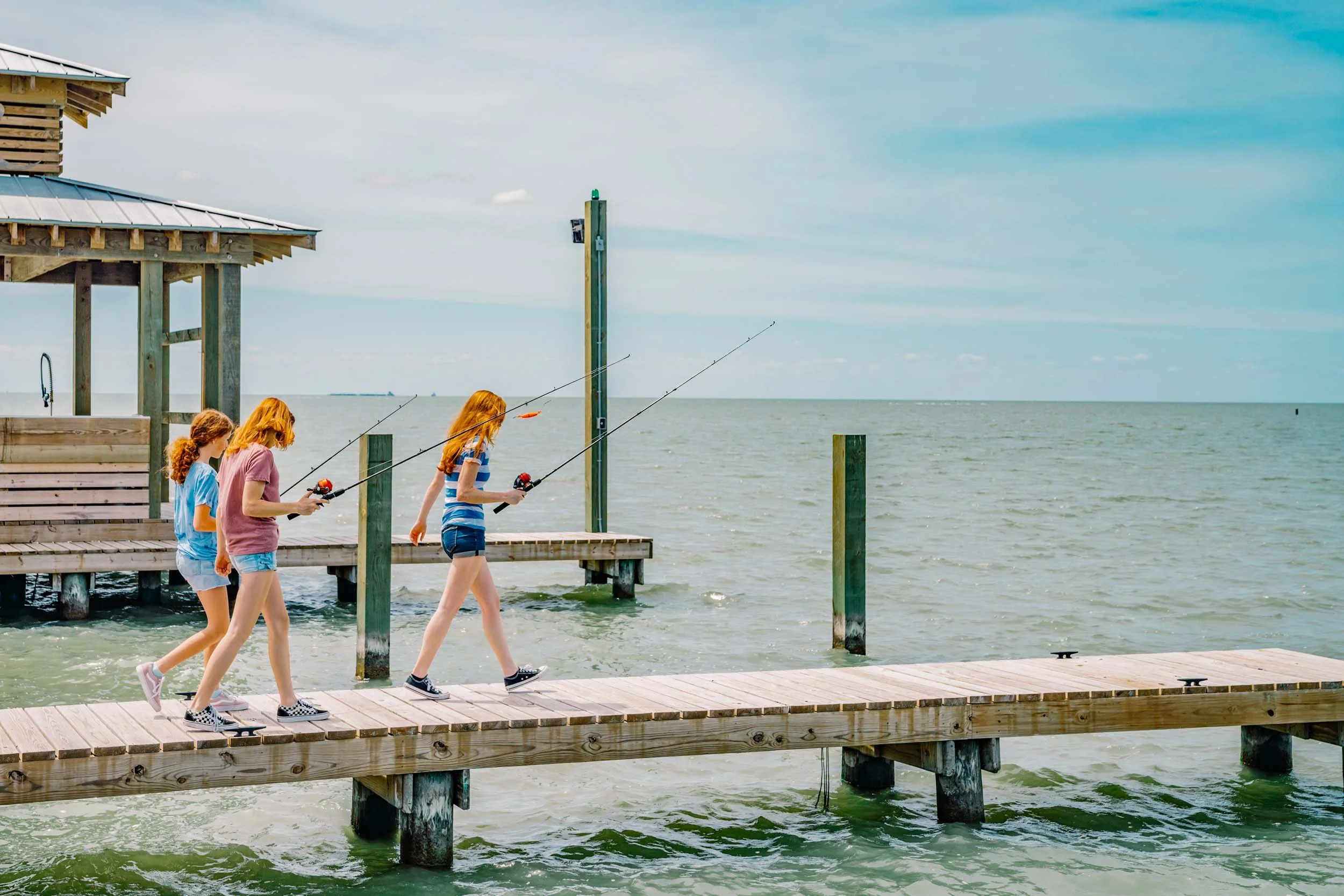 Girls-Walking-on-Fishing-Pier-with-Rods.jpg