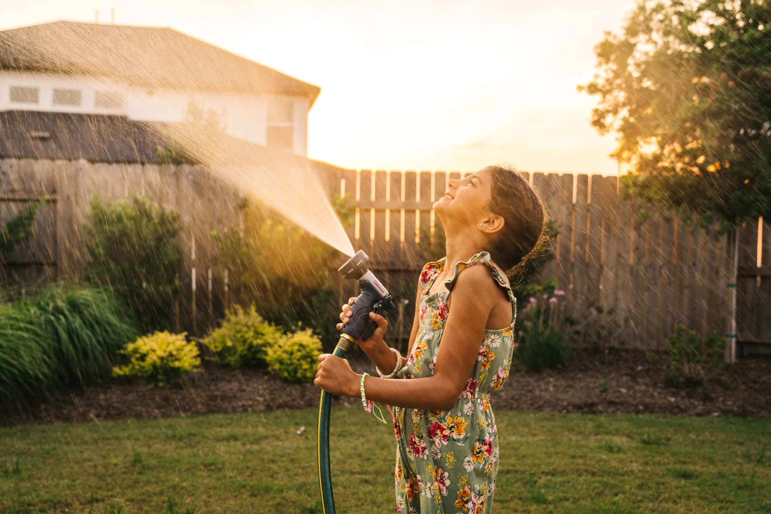 Girl-Plays-with-Garden-Hose-in-Backyard.jpg