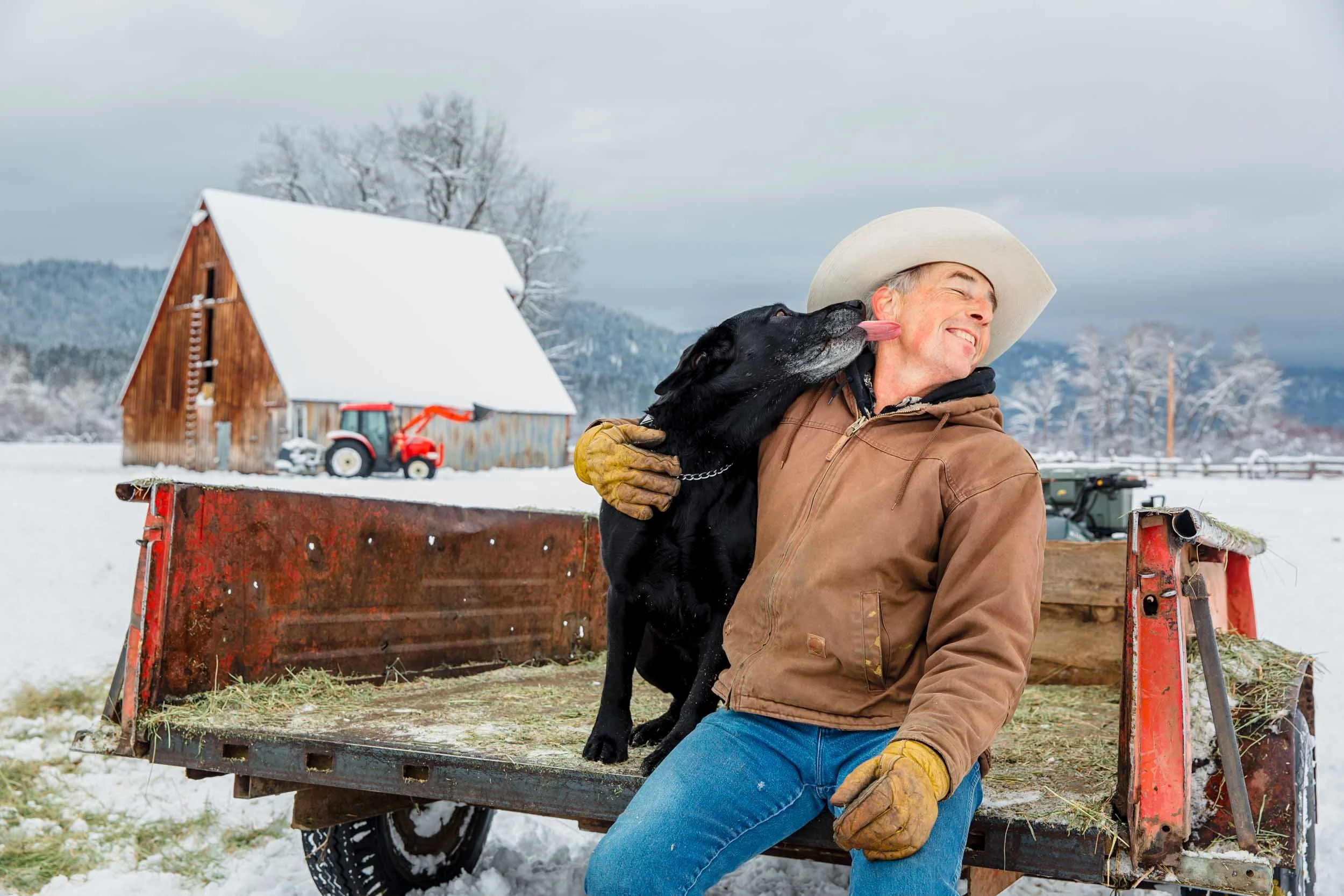 Cowboy-on-Tractor-Trailer-with-Dog-in-Snow.jpg