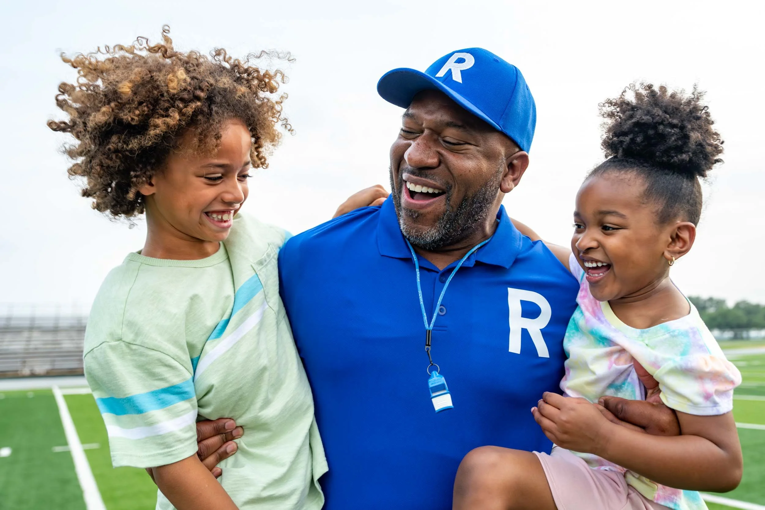 Coach-Carrying-Kids-on-Sports-Field.jpg