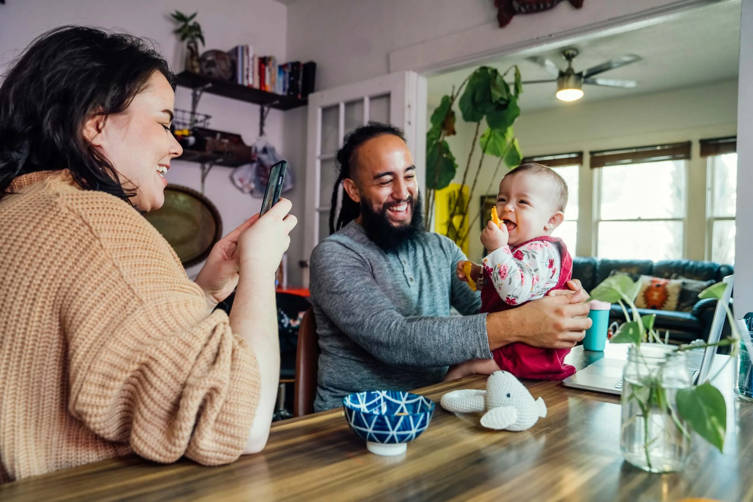 Woman-Taking-Photo-of-Man-and-Baby-in-Home.jpg