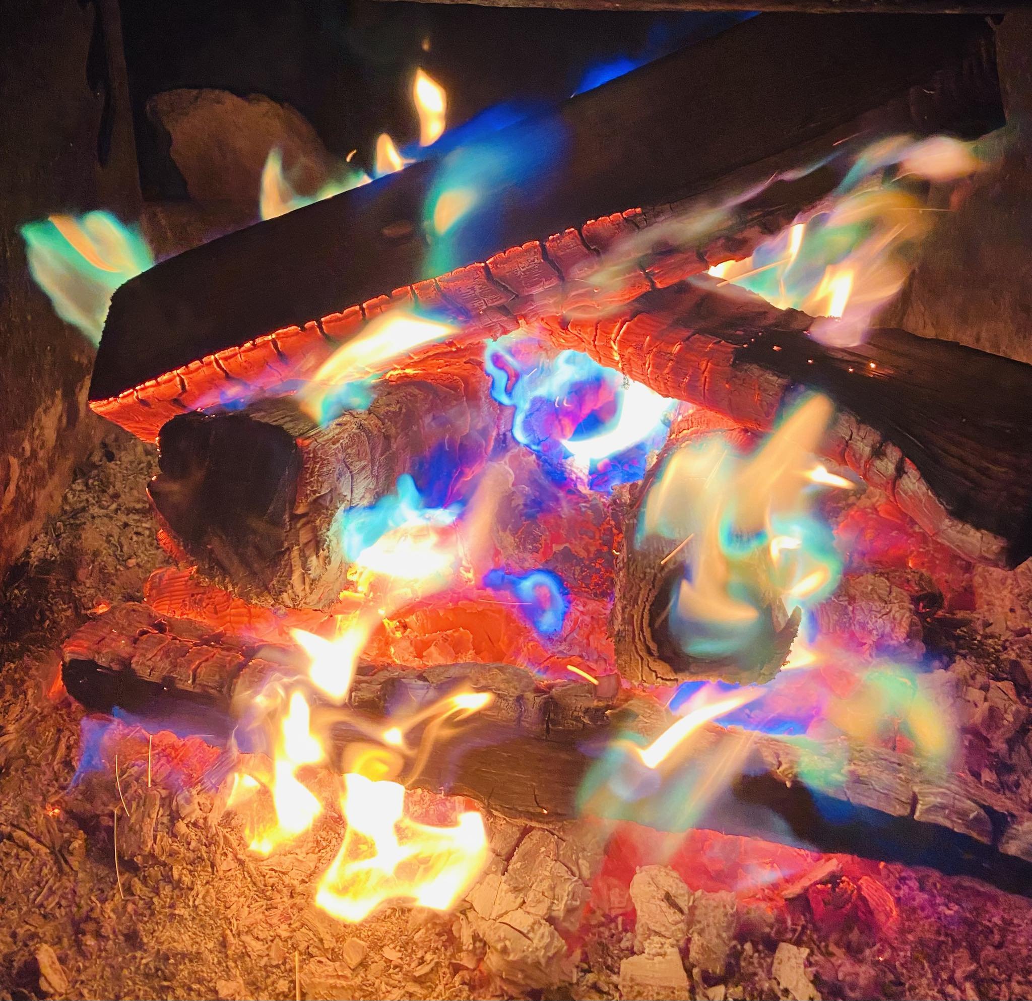 Colorful burning logs with multicolored flames and glowing embers.